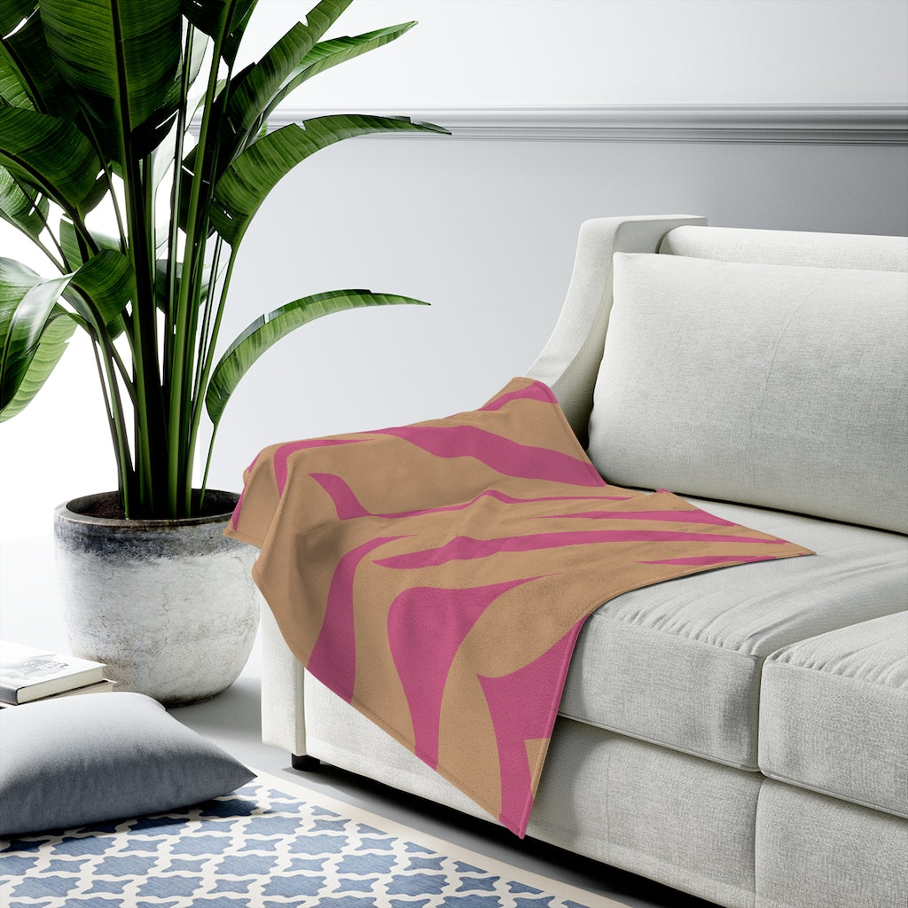 A cozy pink and orange leopard stripes plush throw blanket draped elegantly over a couch, showcasing its soft velveteen texture and vibrant colors.