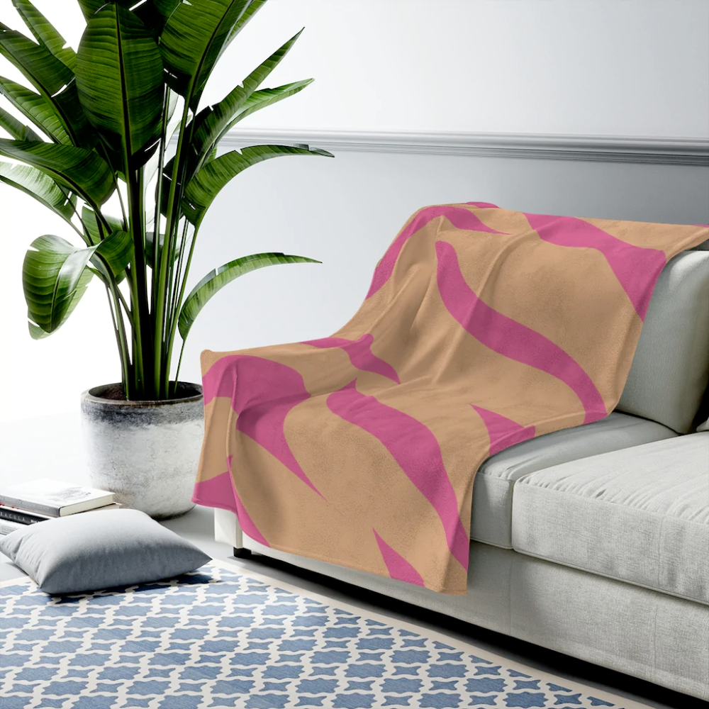 A cozy pink and orange leopard stripes plush throw blanket draped elegantly over a couch, showcasing its soft velveteen texture and vibrant colors.