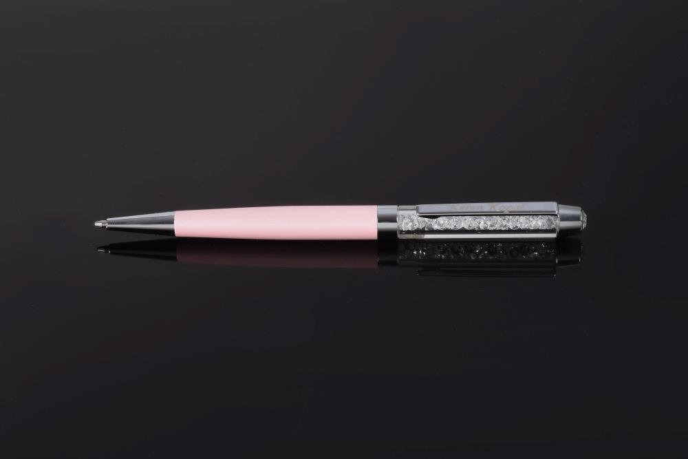 A luxurious pink pen adorned with sparkling Swarovski crystals, elegantly displayed in a black gift box.