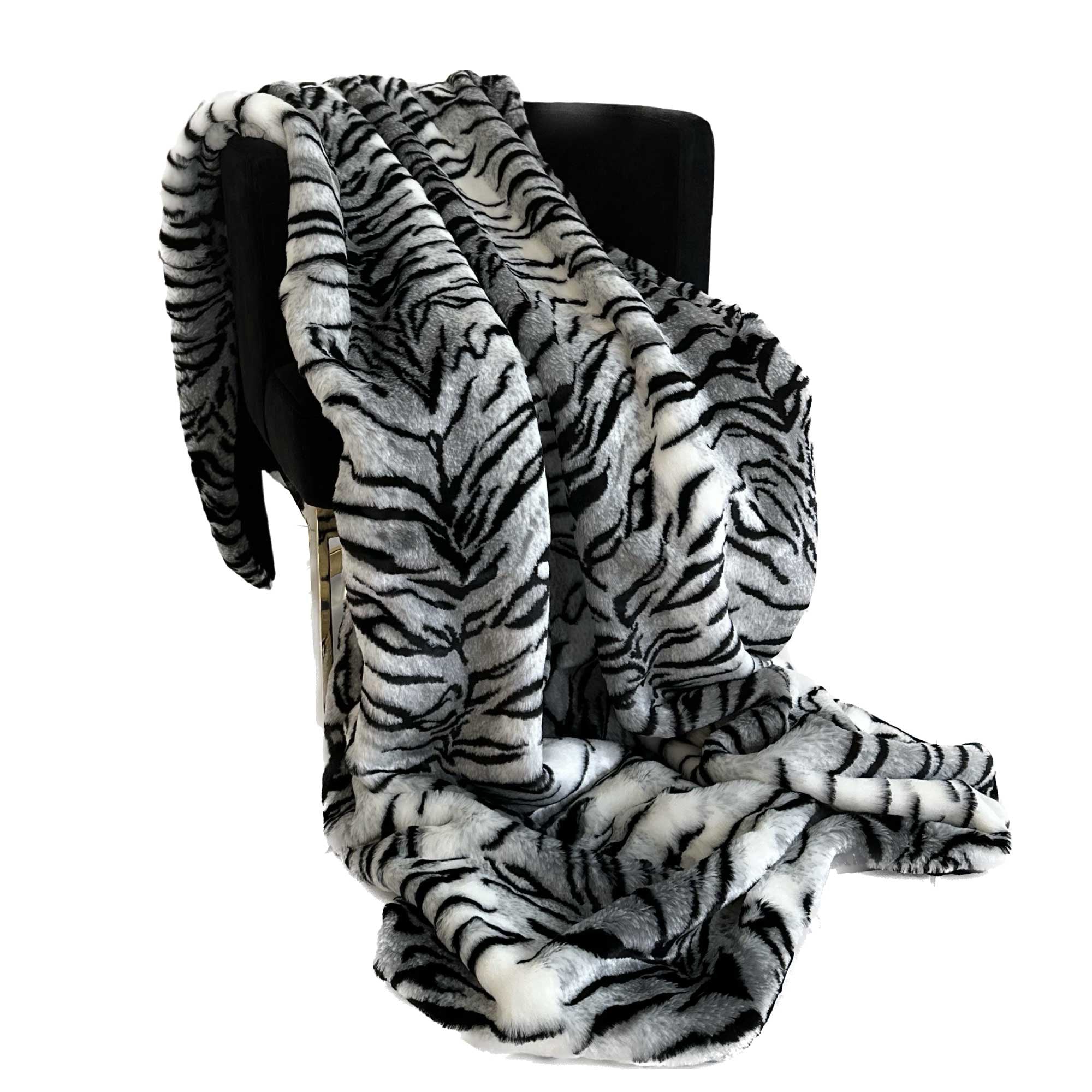 Plutus Black and White Zebra Faux Fur Luxury Throw Blanket draped elegantly over a sofa, showcasing its fluffy texture and stylish design.