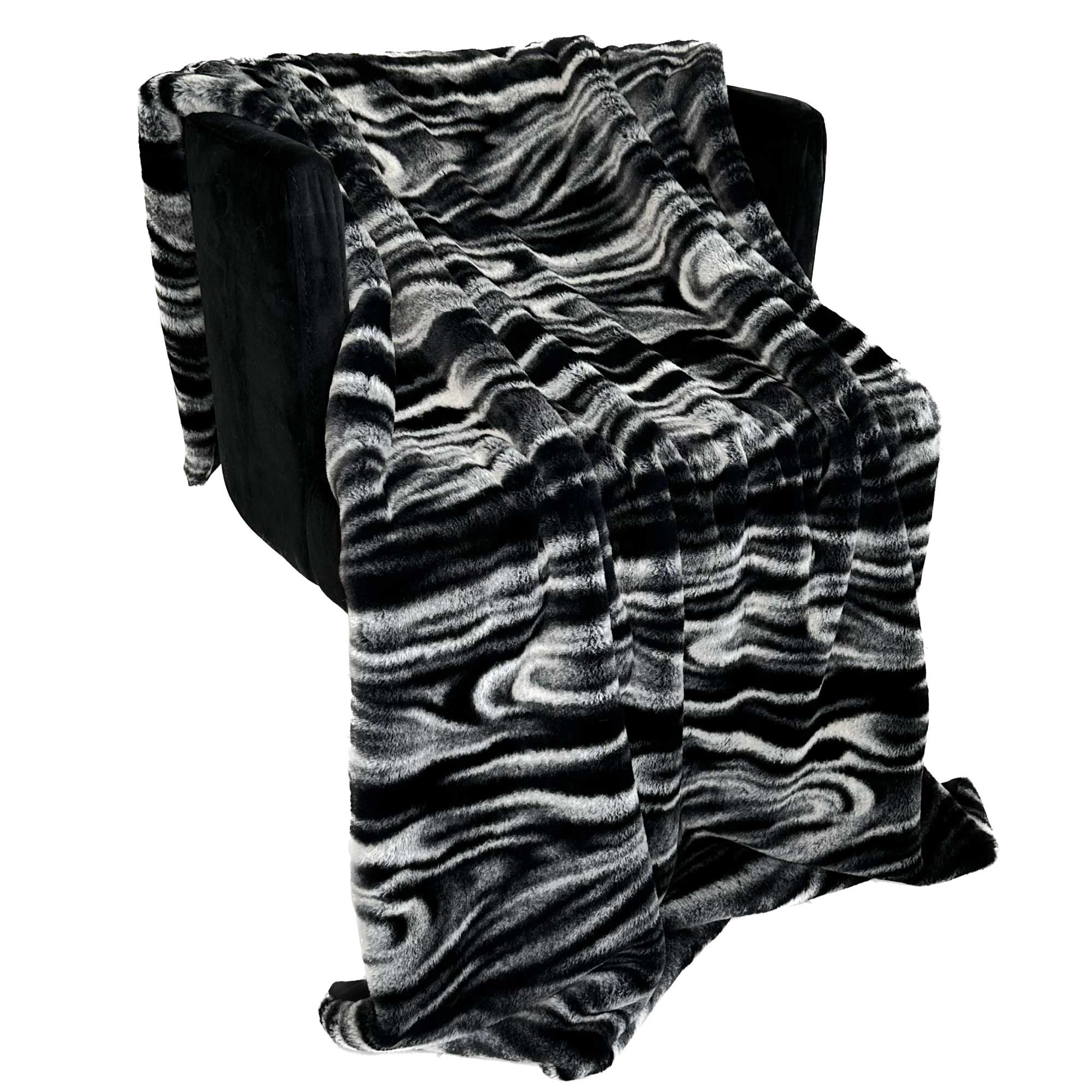 Plutus Black White Galaxy Faux Fur Luxury Throw Blanket draped elegantly over a sofa, showcasing its plush texture and stylish design.