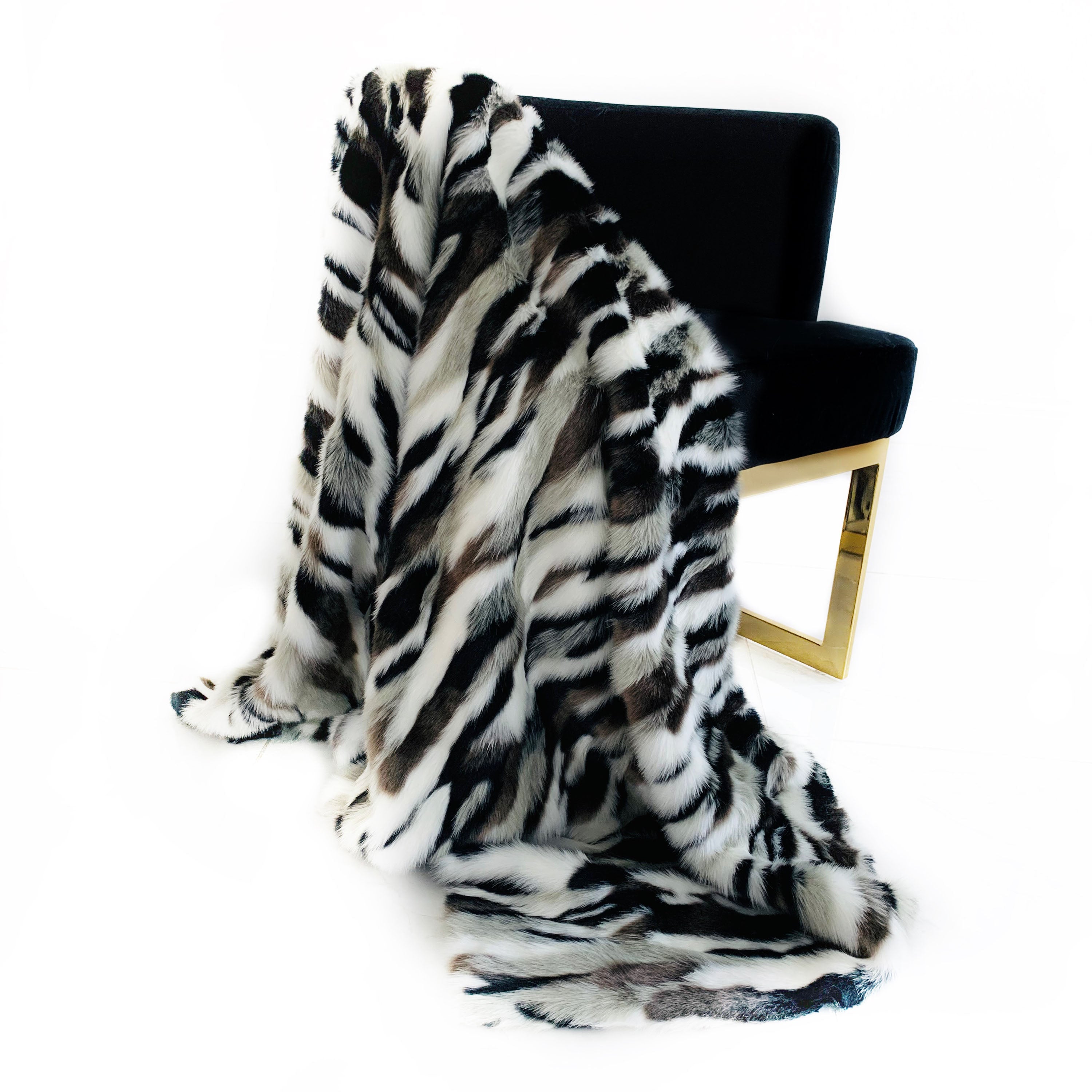 Plutus Black and White Zebra Faux Fur Luxury Throw Blanket draped elegantly on a sofa, showcasing its plush texture and stylish design.