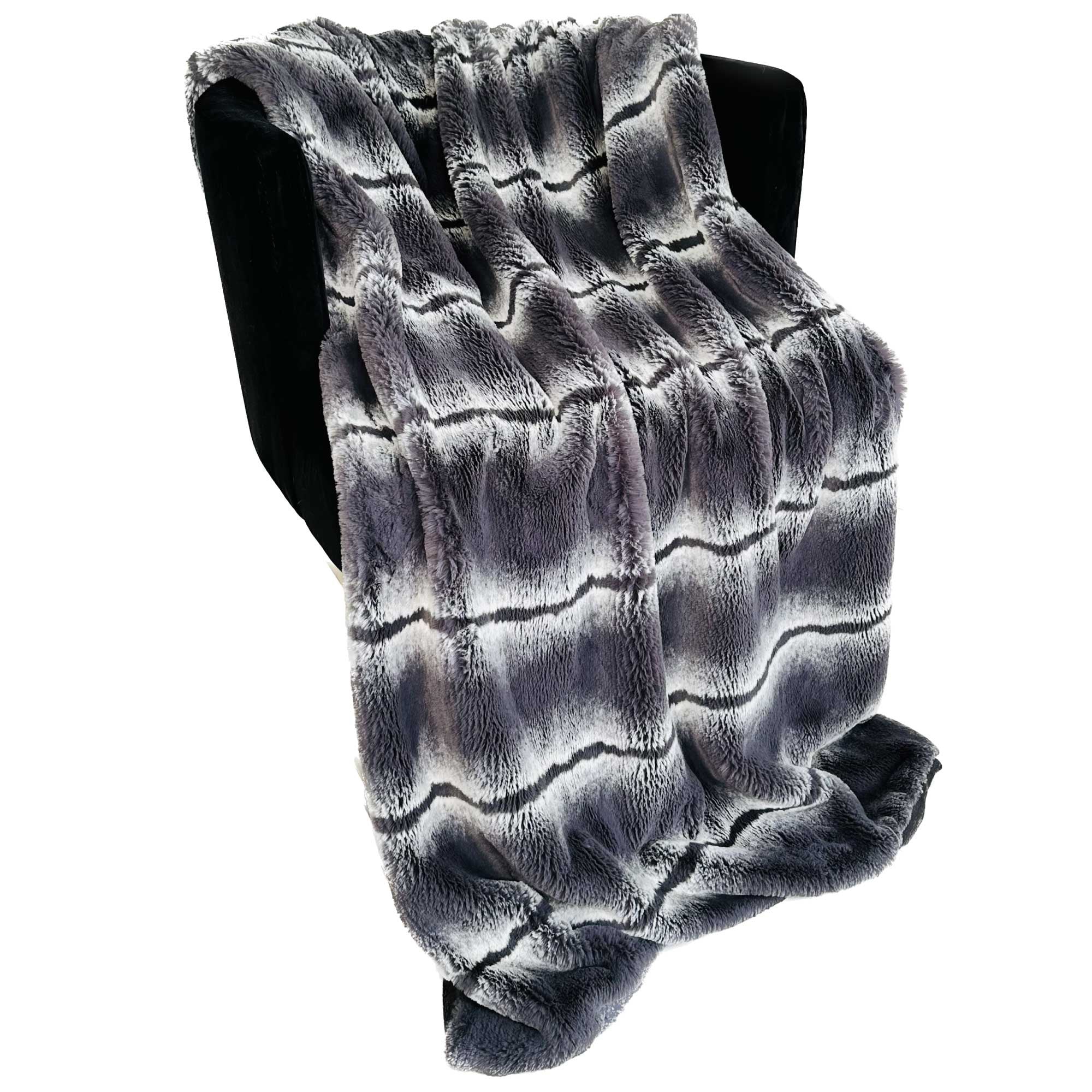 Plutus Charcoal Fluffy Fields Faux Fur Luxury Throw Blanket draped elegantly on a sofa, showcasing its soft texture and rich charcoal color.