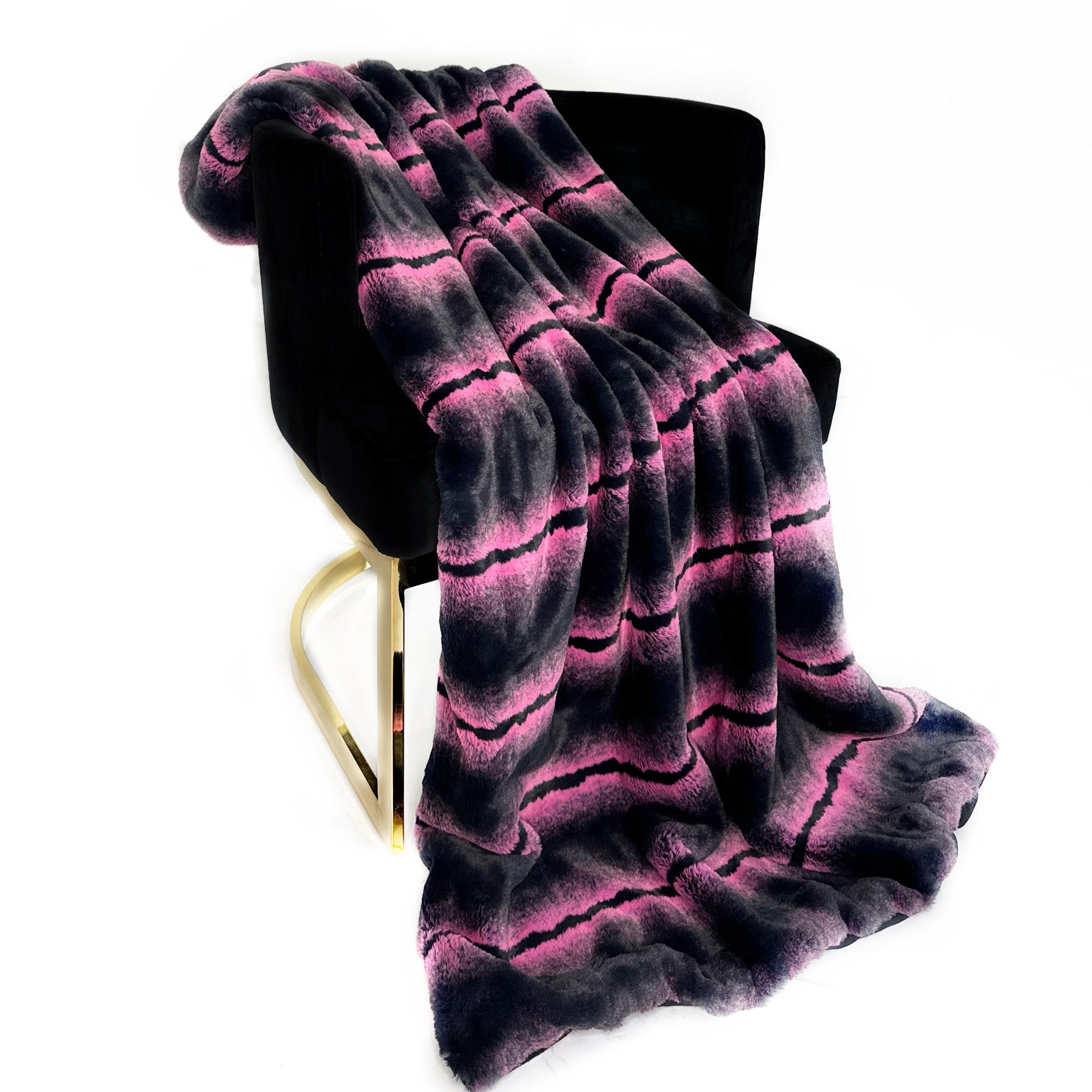 Plutus Fuchsia Black Fluffy Fields Faux Fur Luxury Throw Blanket draped elegantly over a chair, showcasing its plush texture and vibrant color.