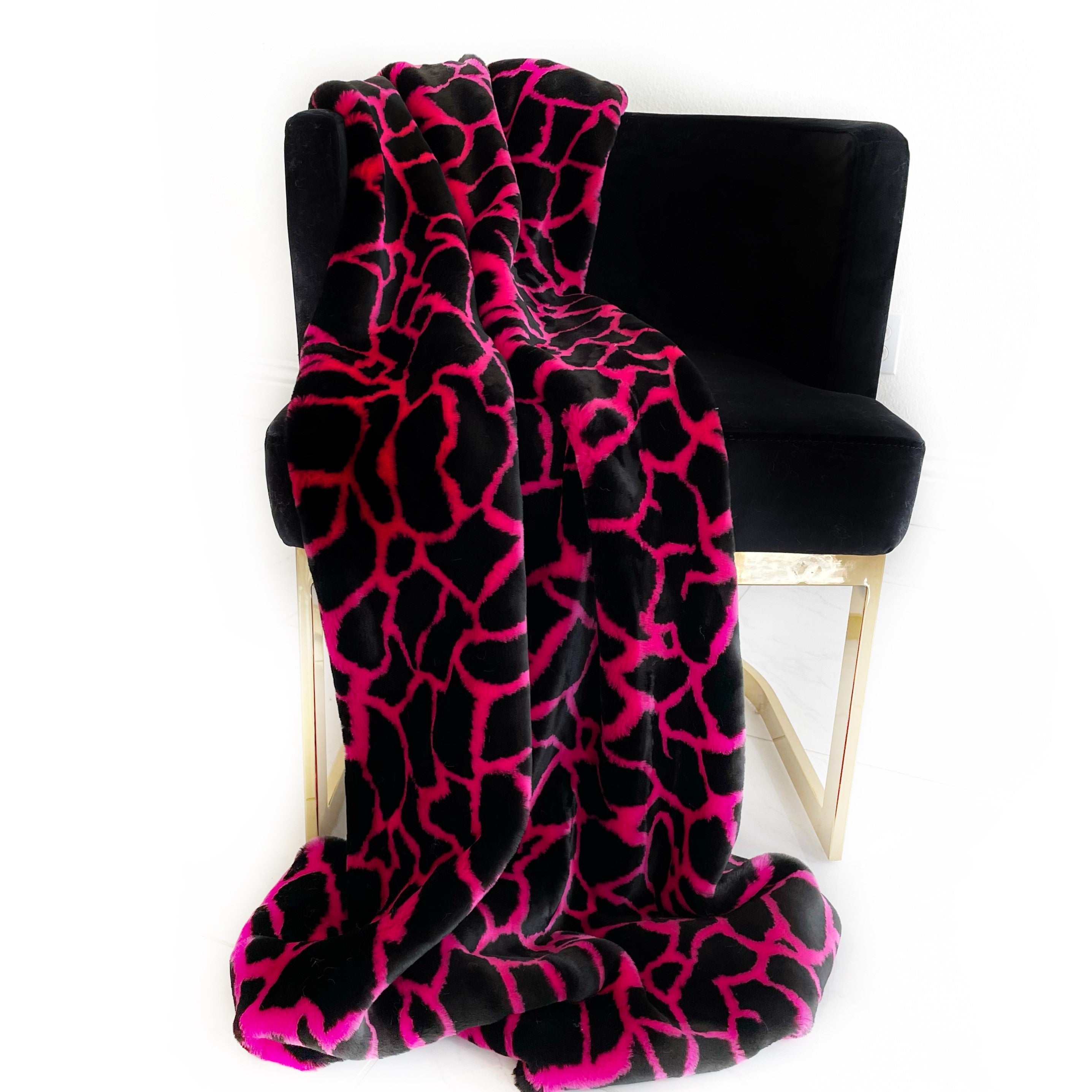 Plutus Pink Black Plush Faux Fur Luxury Throw Blanket draped elegantly over a couch, showcasing its soft texture and stylish color combination.