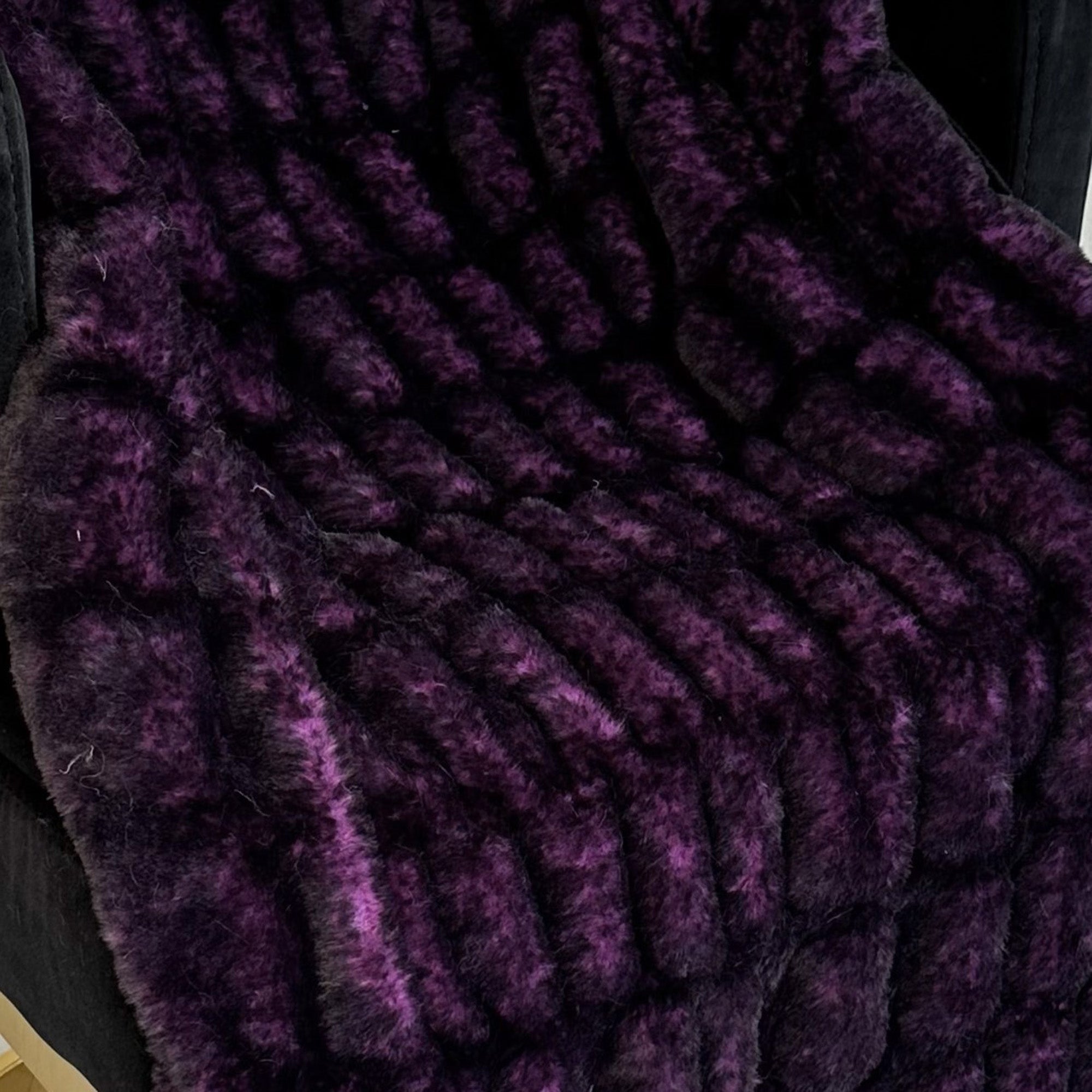 Plutus Purple Plush Pelt Faux Fur Luxury Throw Blanket draped elegantly on a couch, showcasing its rich purple color and soft texture.