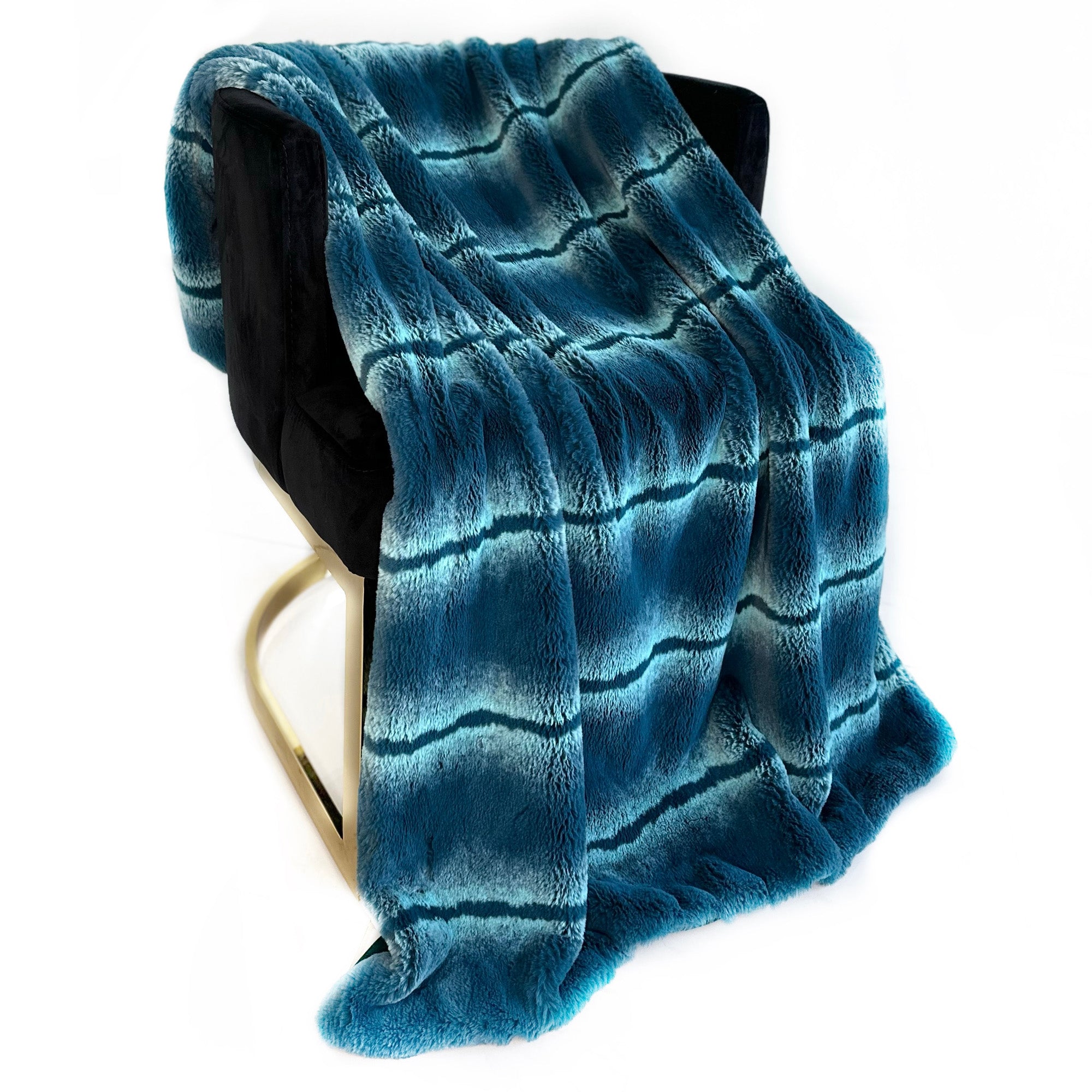 Plutus Teal Fluffy Fields Faux Fur Luxury Throw Blanket draped elegantly on a couch, showcasing its soft texture and vibrant teal color.