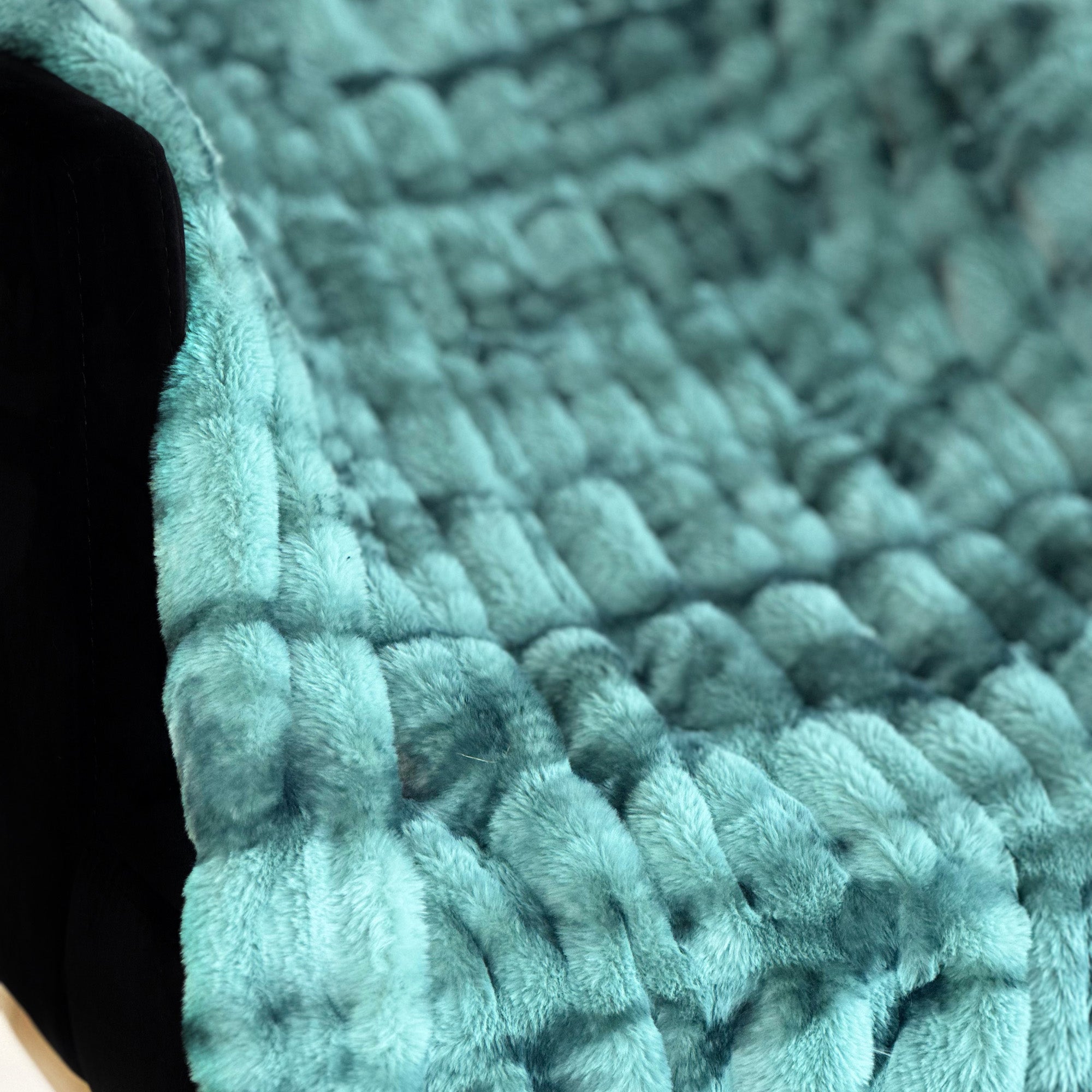 Plutus Teal Sherpa Faux Fur Luxury Throw Blanket draped elegantly on a couch, showcasing its soft texture and vibrant teal color.