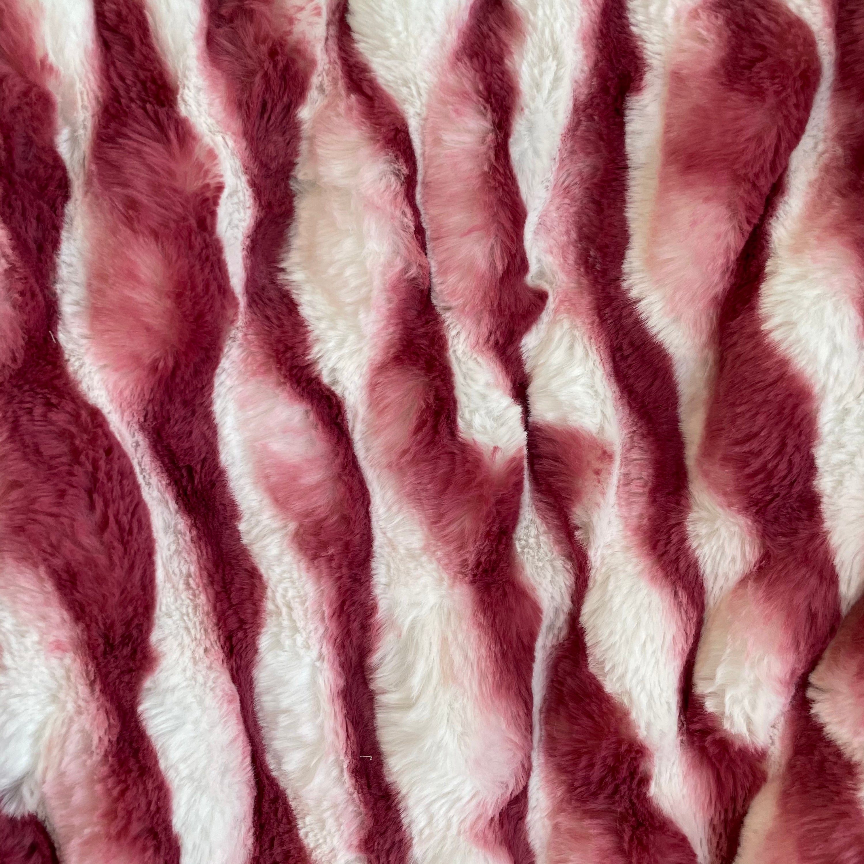 Plutus White Berry Snow Chinchilla Faux Fur Luxury Throw Blanket draped elegantly over a sofa, showcasing its soft texture and trendy color.