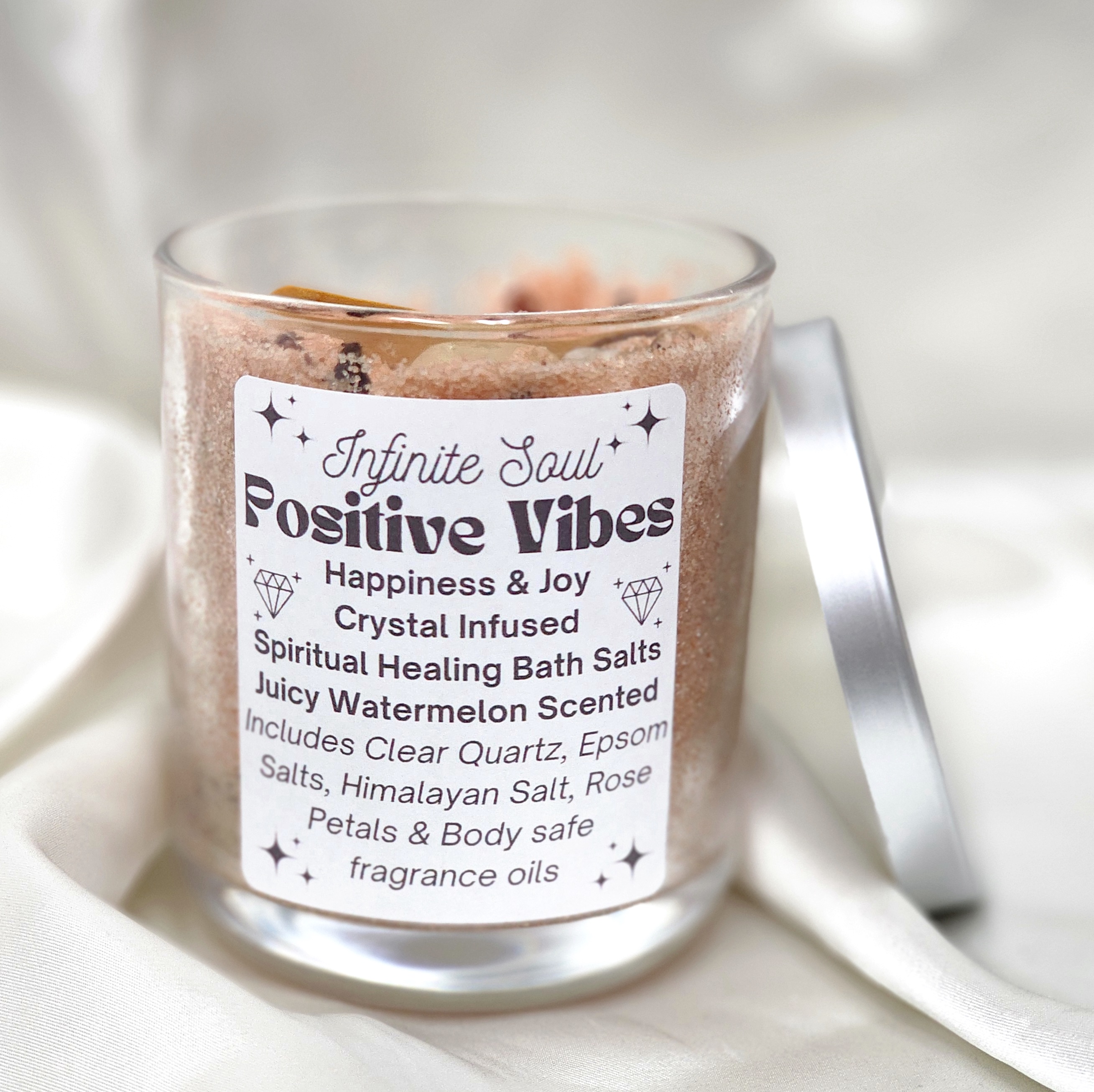 A jar of Positive Vibes Happiness and Joy Crystal Infused Bath Salts with rose petals and Citrine crystals, featuring a juicy watermelon scent.
