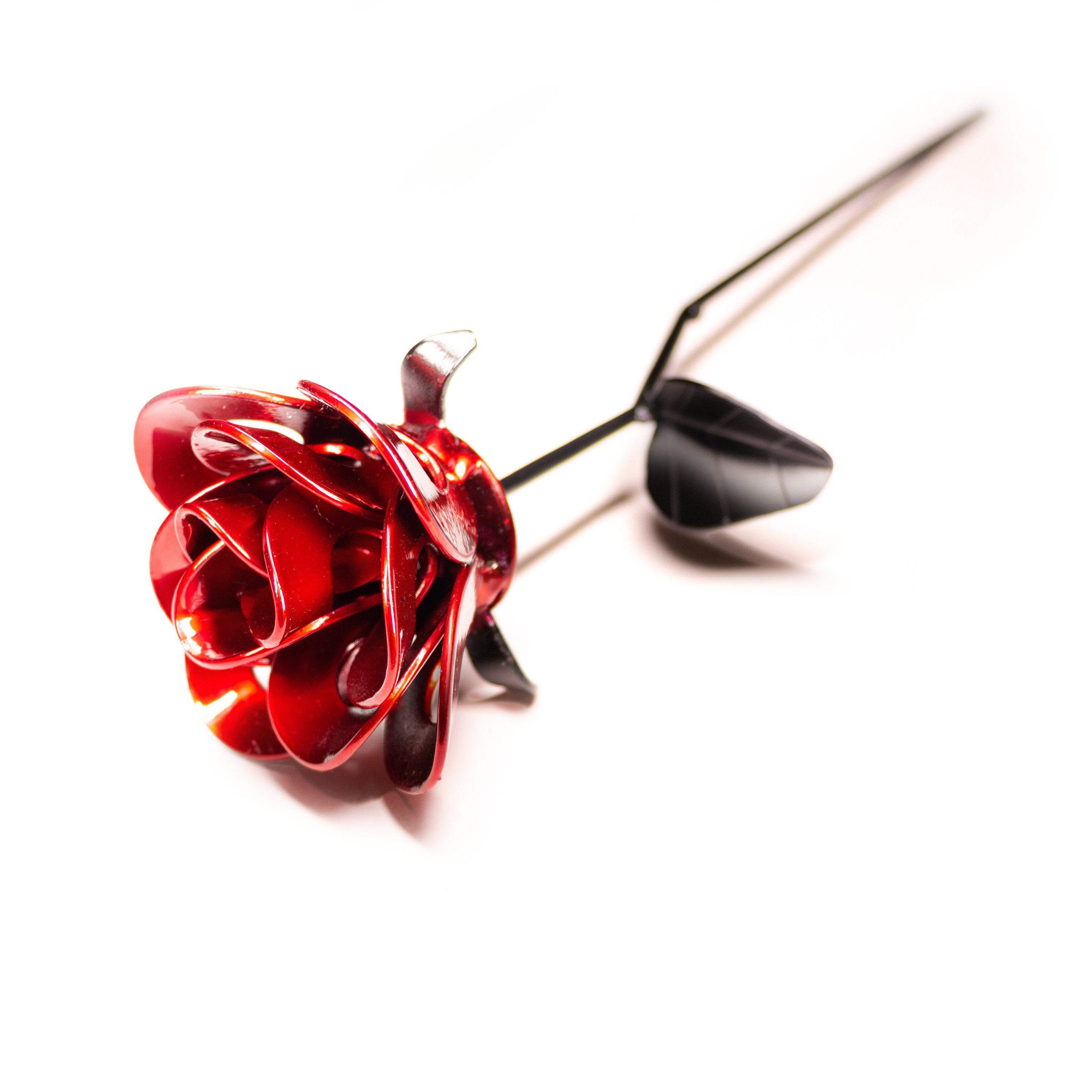 A handcrafted red and black metal rose made from recycled washers and wire, showcasing a lustrous metallic finish and a light green stem, elegantly packaged in a clear gift box.