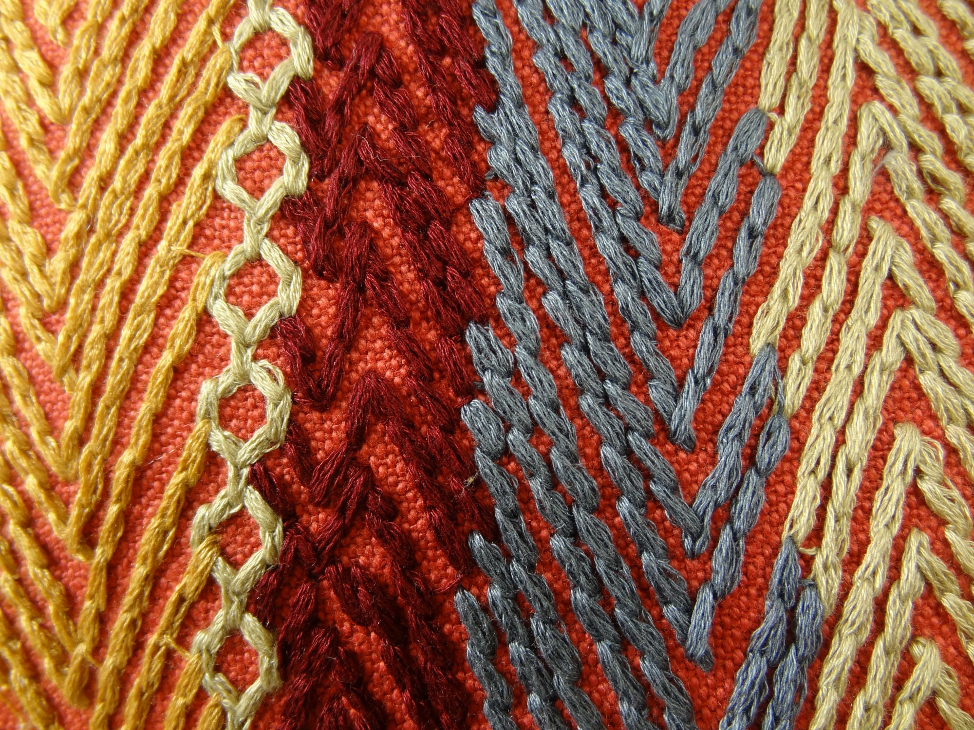 A luxurious handmade pillow featuring a vibrant striped pattern in red, blue, and orange, showcasing its elegant design and quality craftsmanship.