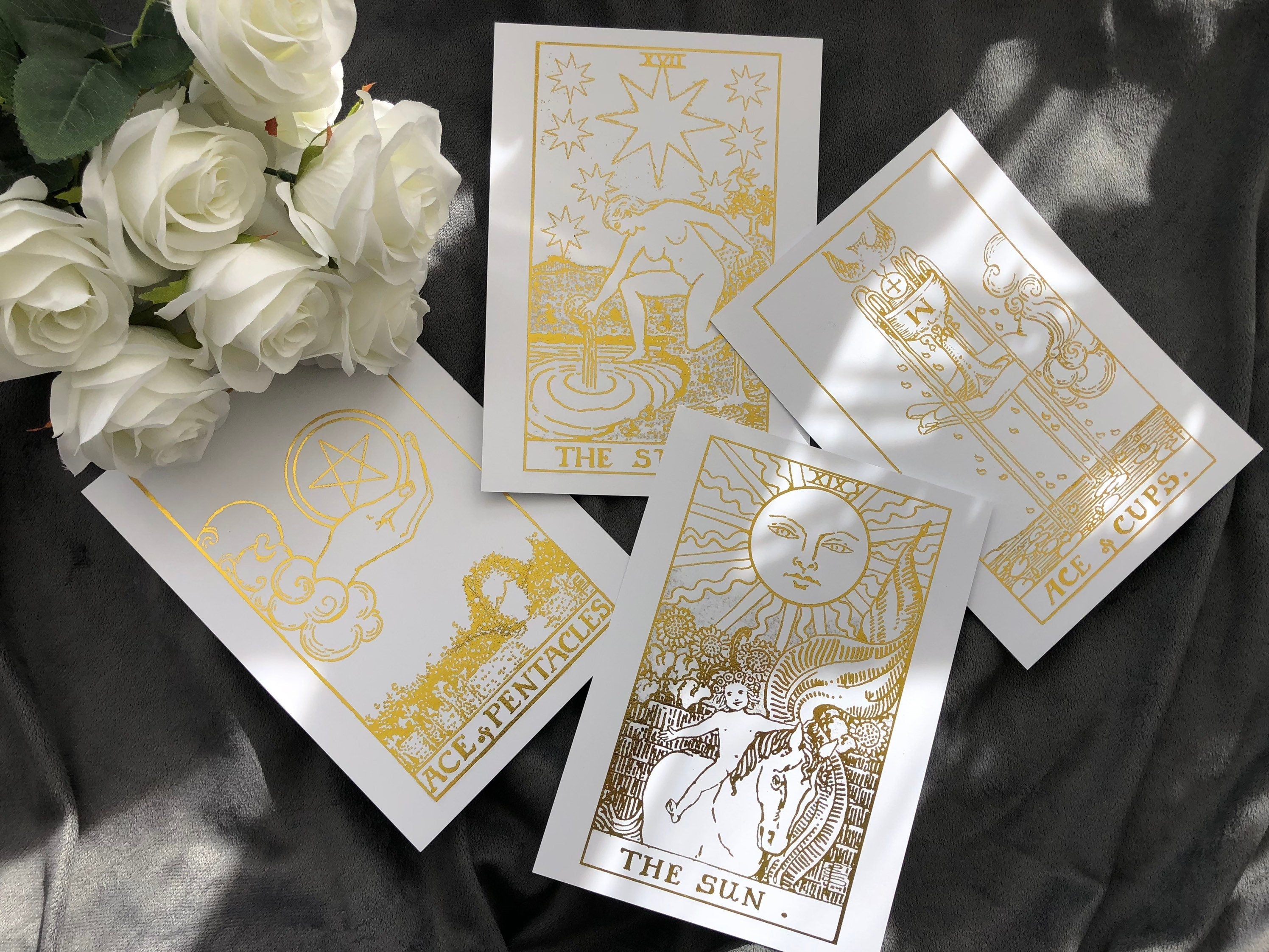 Set of 4 tarot card foil prints featuring Ace of Cups, The Sun, The Star, and Ace of Pentacles in white and gold accents.