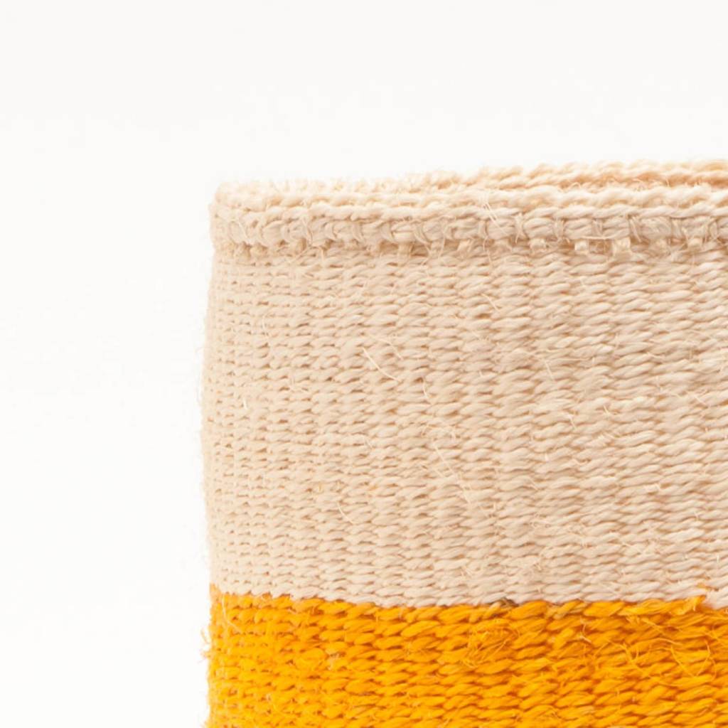 A set of three handwoven African sisal storage baskets in varying sizes, showcasing natural and hand-dyed colors, perfect for stylish organization.