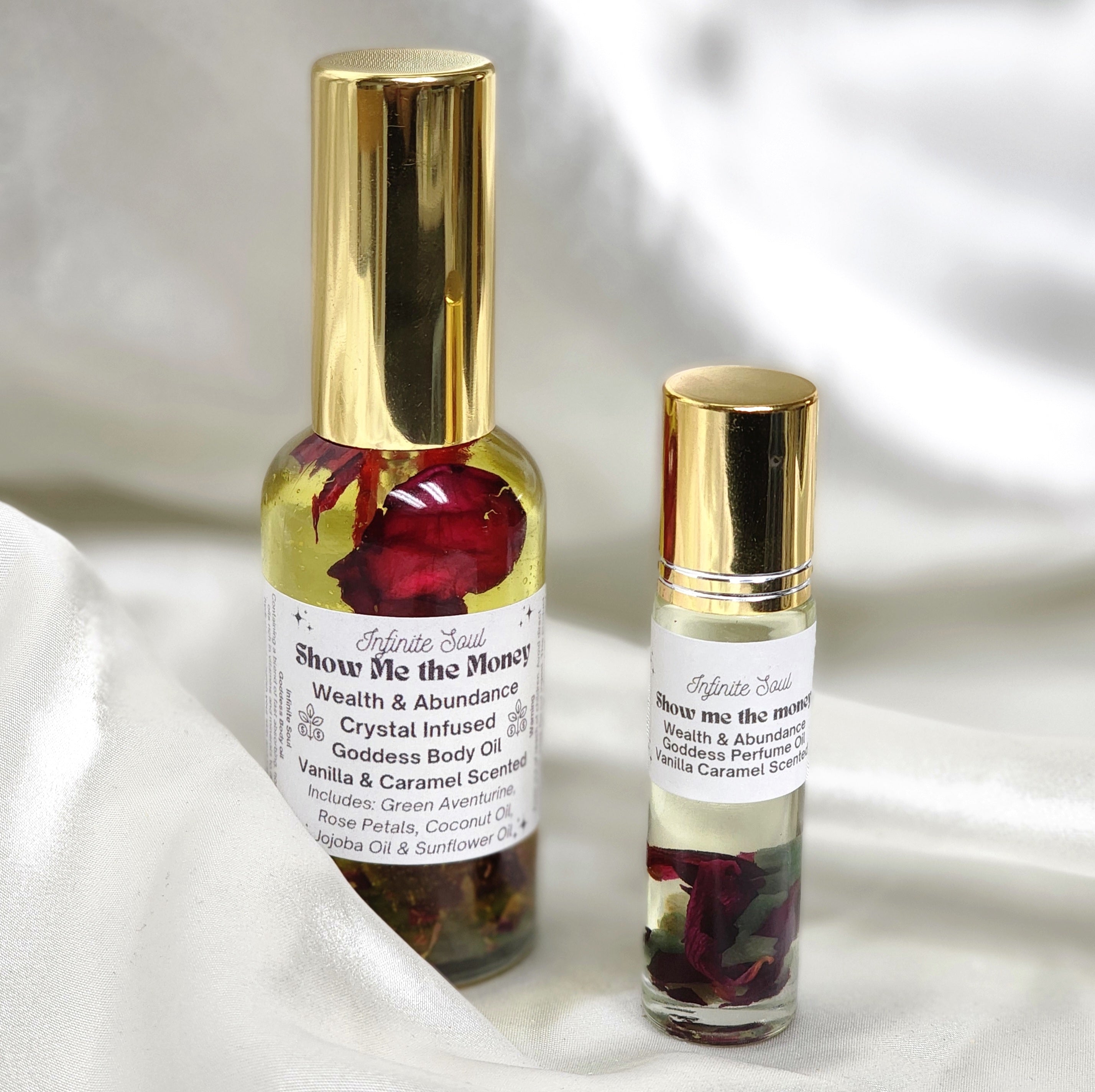 A bottle of Wealth & Abundance Crystal Infused Goddess Body Oil with Citrine chips, surrounded by rose petals and chamomile buds.