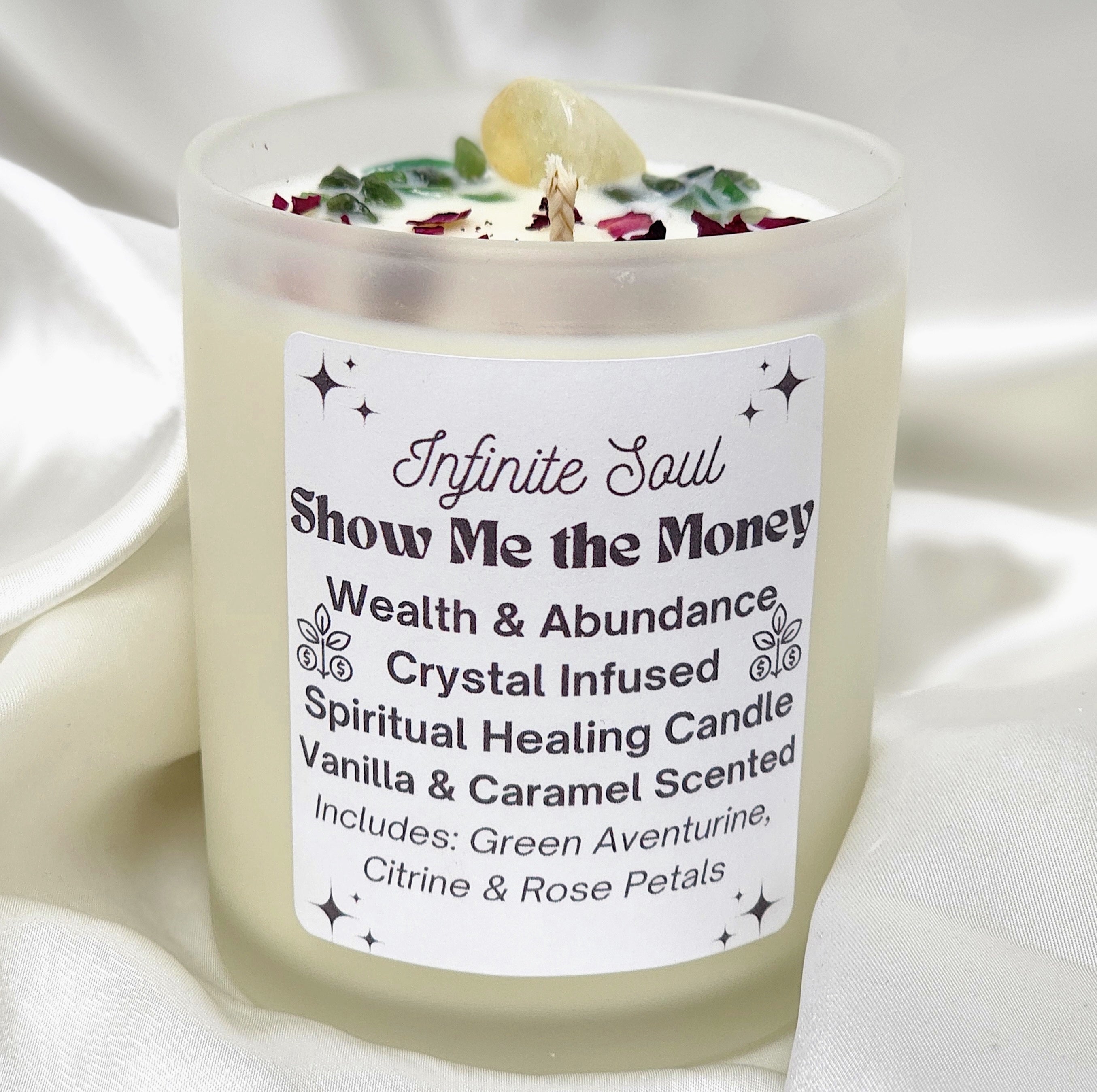 Show Me the Money candle with Green Aventurine and Citrine crystals, in a clear jar, surrounded by rose petals.