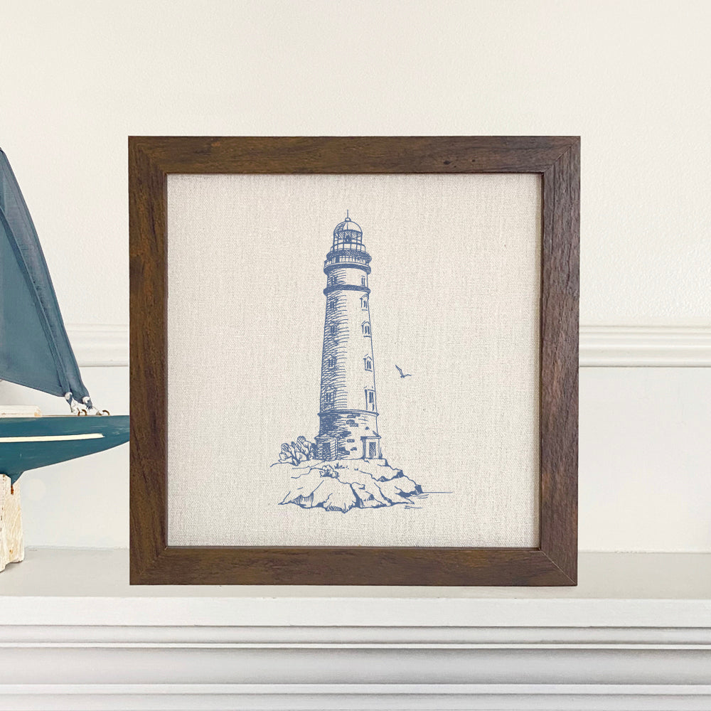 A round framed sign featuring a sketched lighthouse design, with a natural wood frame available in walnut or white-washed finish.
