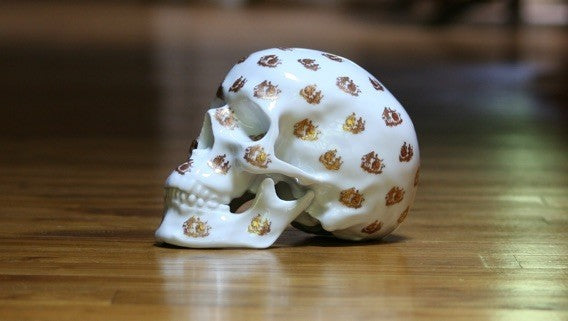 A unique Skull Salutation sculpture by NooN, crafted from extra white porcelain, showcasing intricate artist decor on a skull design.
