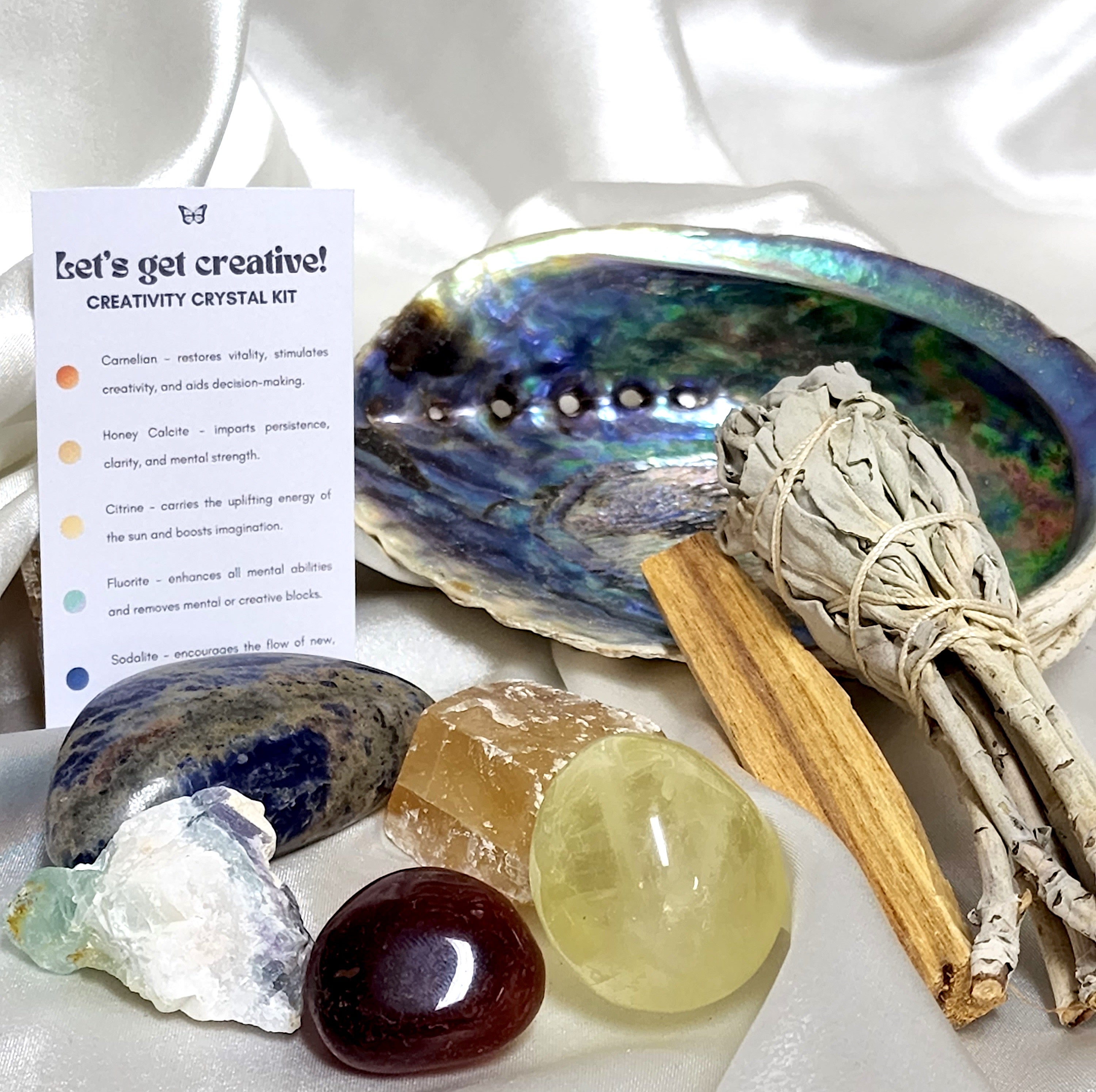 Smudge Kit featuring a large sage smudge stick, Palo Santo, and an abalone shell with various crystals for creativity.