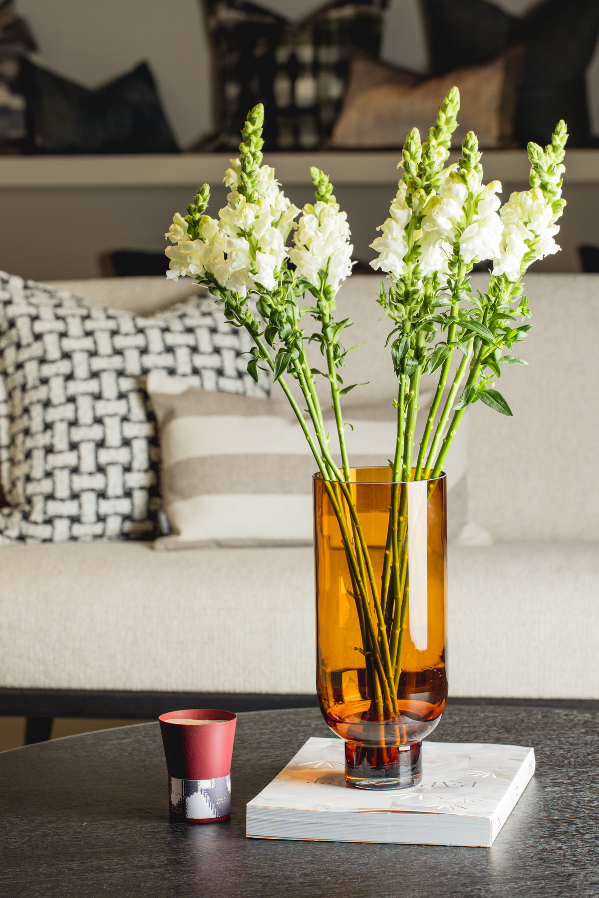 Sober modern glass vase in amber color, cylindrical shape with a solid narrow base, elegantly showcasing its curves.