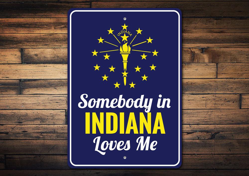 A decorative aluminum sign reading 'Somebody in Indiana Loves Me', showcasing vibrant colors and a charming design, perfect for home decor.