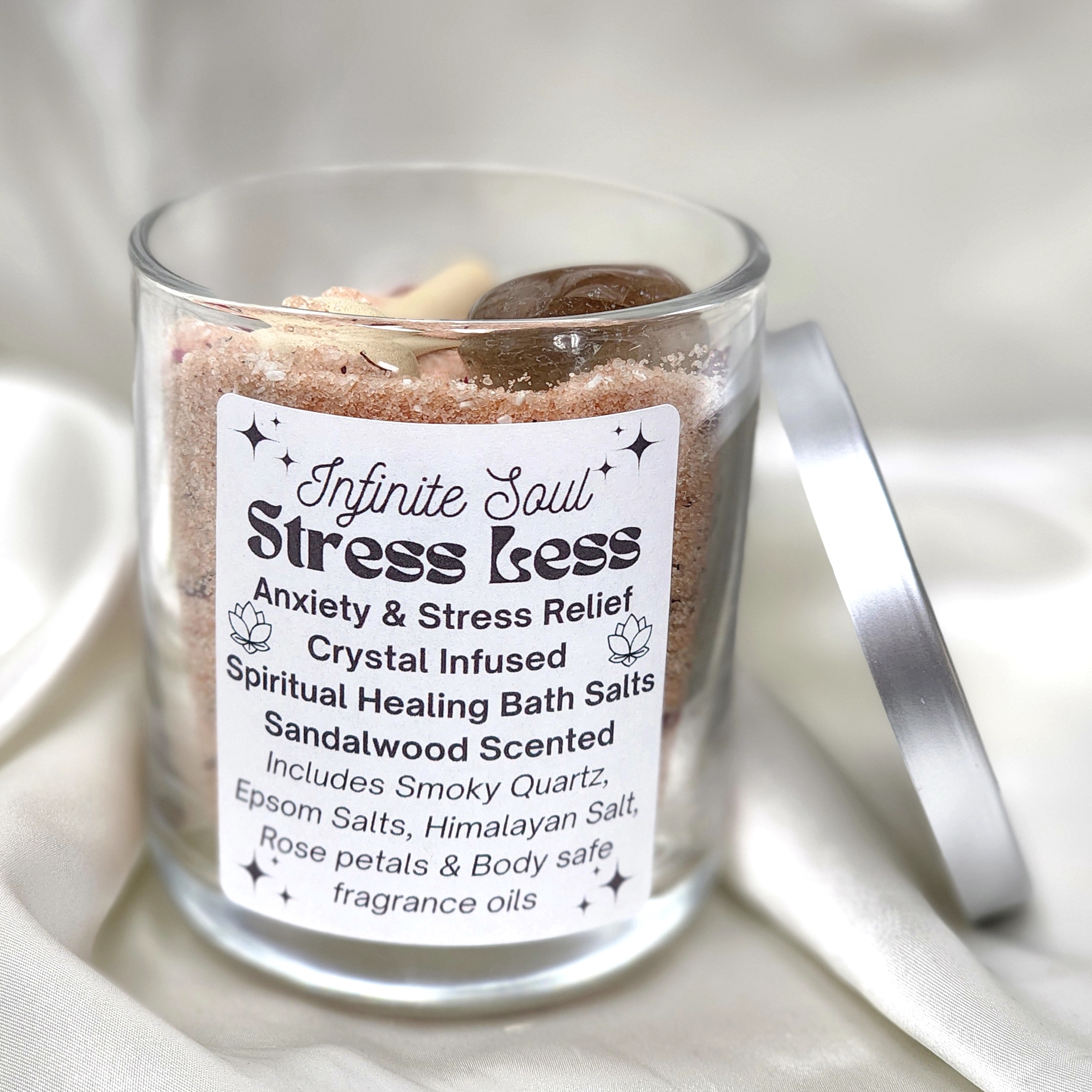 A jar of Stress Less Anxiety & Stress Relief Crystal Infused Bath Salts with wooden spoon and colorful petals, showcasing its natural ingredients.