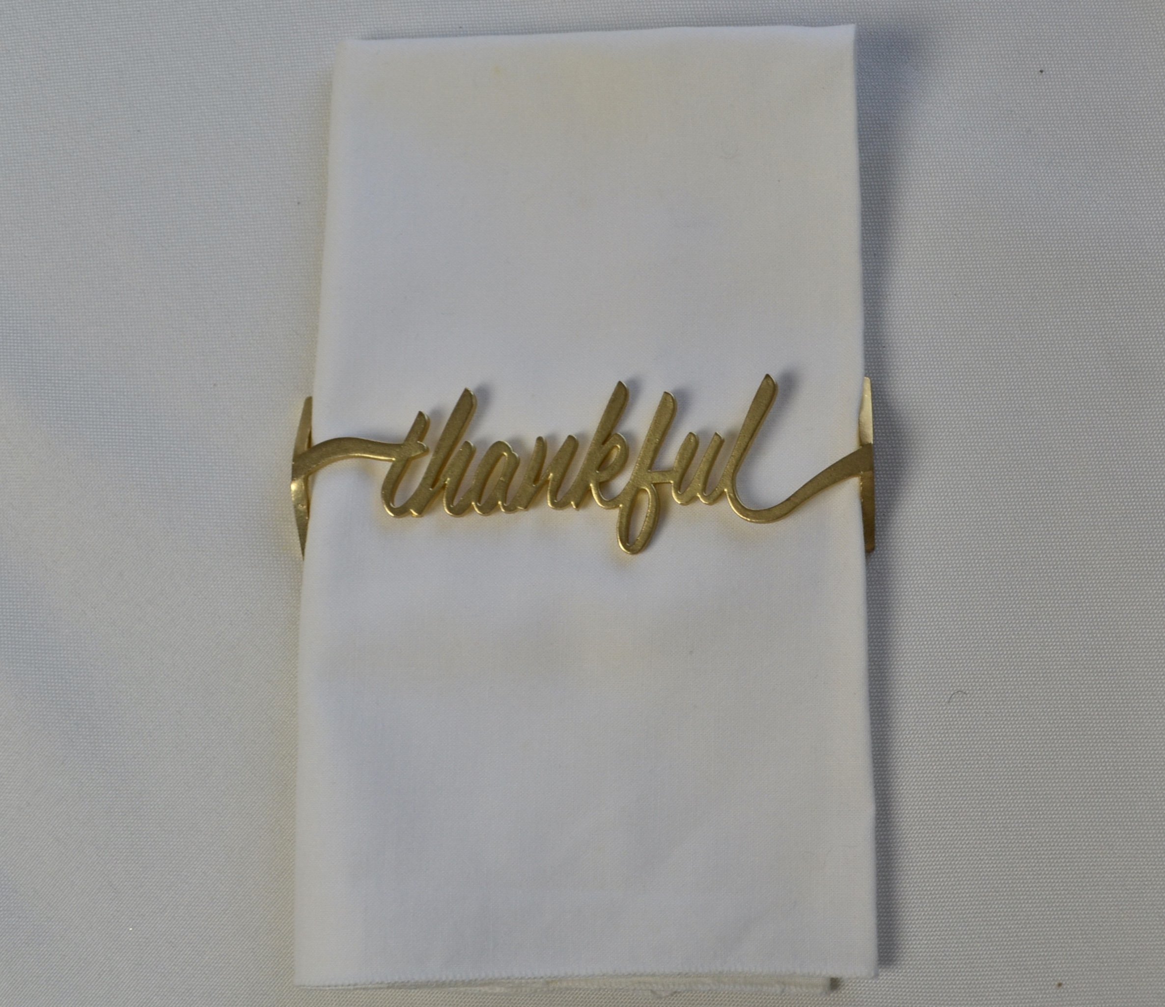 Thankful Wrap Matte Gold napkin wraps elegantly encircling napkins, showcasing a chic matte gold finish for stylish dining decor.