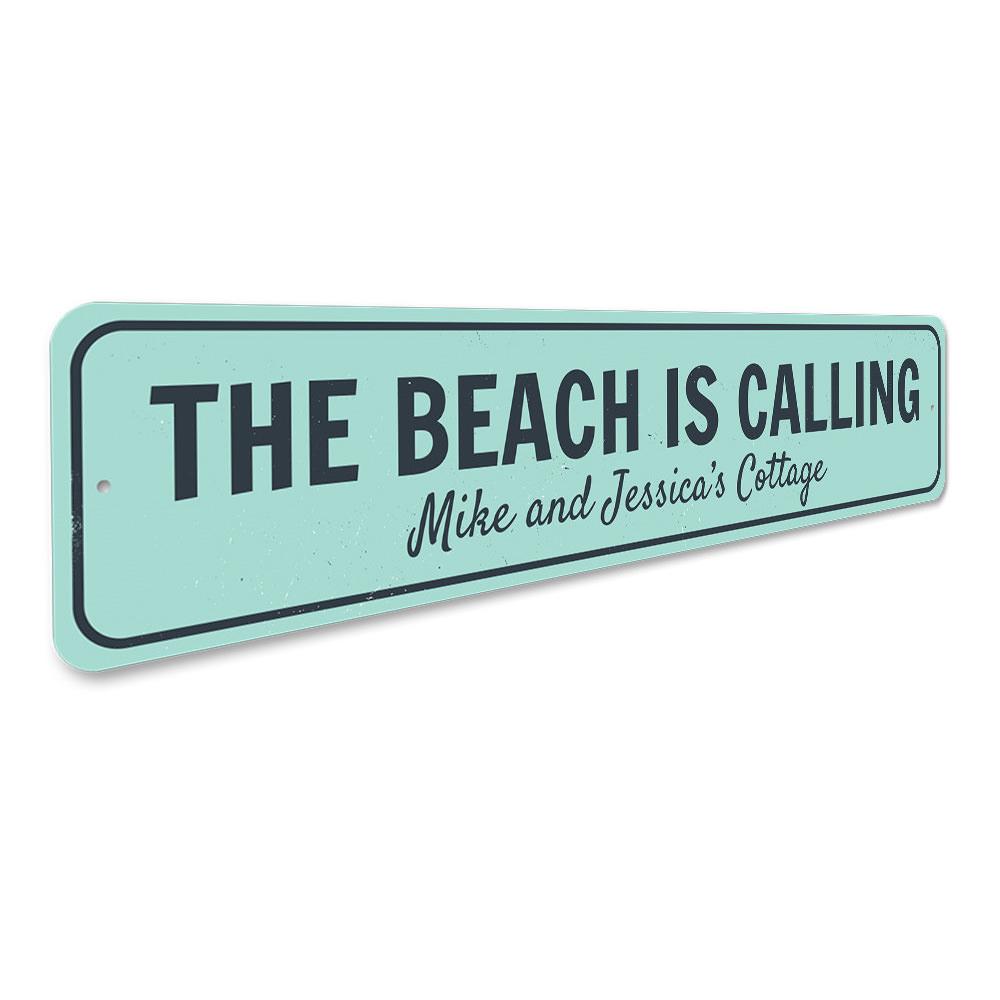 A decorative aluminum sign reading 'The Beach Is Calling', featuring a coastal design, perfect for home decor.