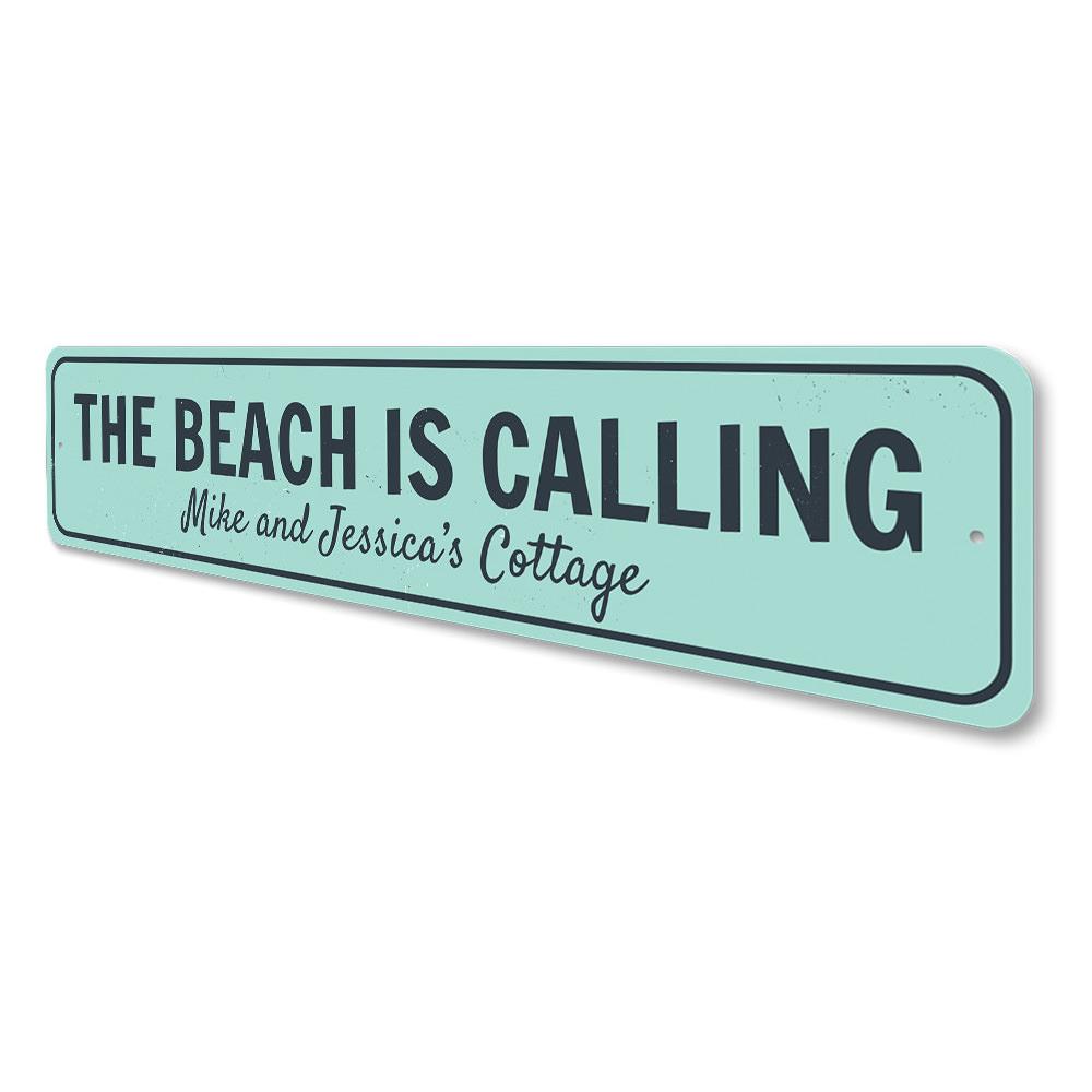 A decorative aluminum sign reading 'The Beach Is Calling', featuring a coastal design, perfect for home decor.