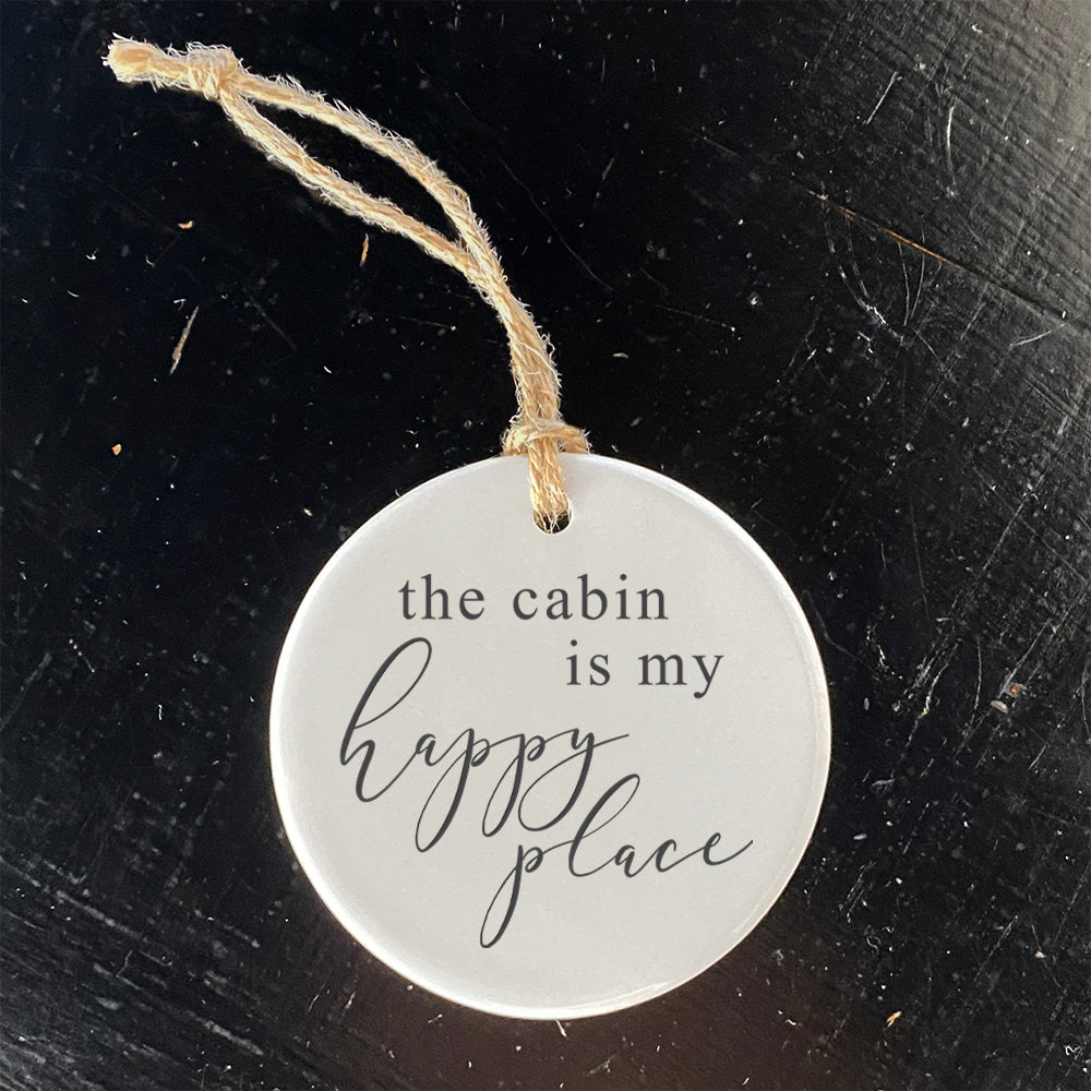 A beautifully crafted porcelain ornament featuring the phrase 'The Cabin is my Happy Place', showcasing vibrant colors and a smooth finish.