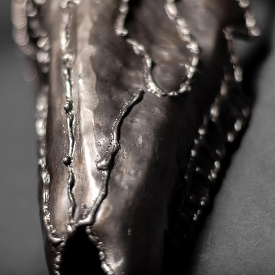 Handcrafted metal sculpture of an eight-point buck skull, showcasing intricate details and a rustic finish.