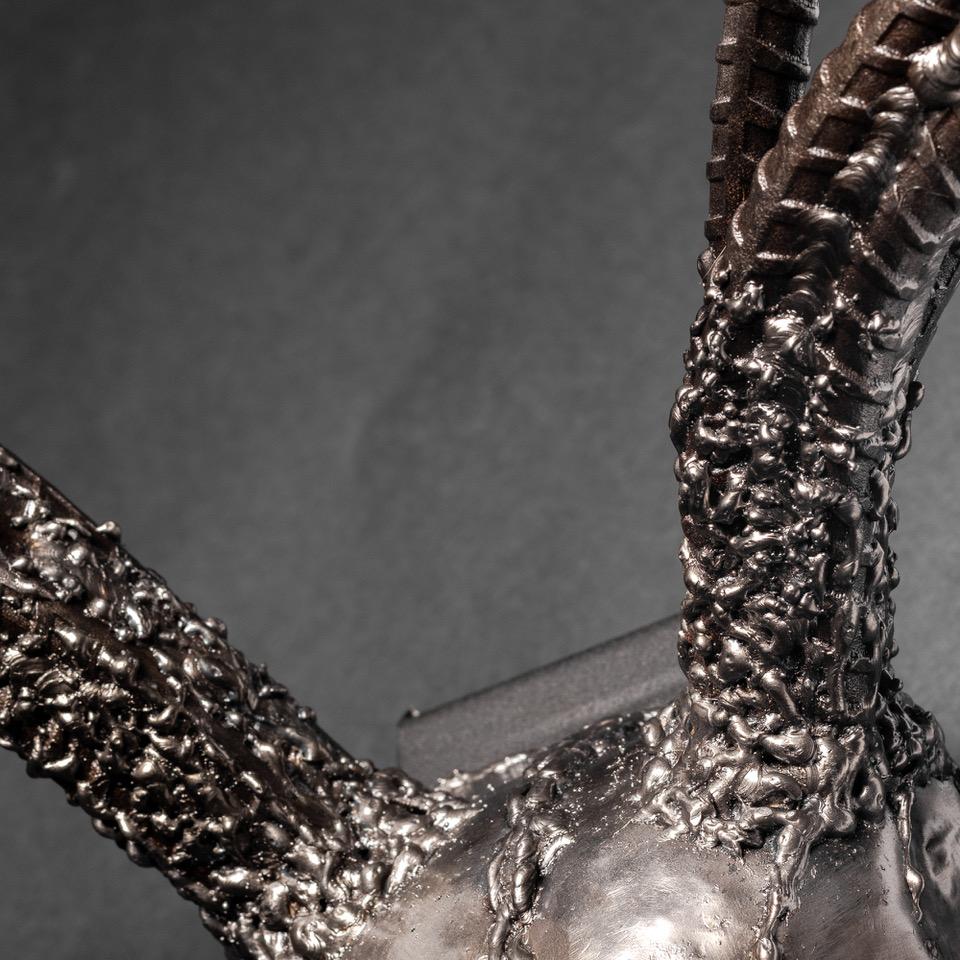 Handcrafted metal sculpture of an eight-point buck skull, showcasing intricate details and a rustic finish.