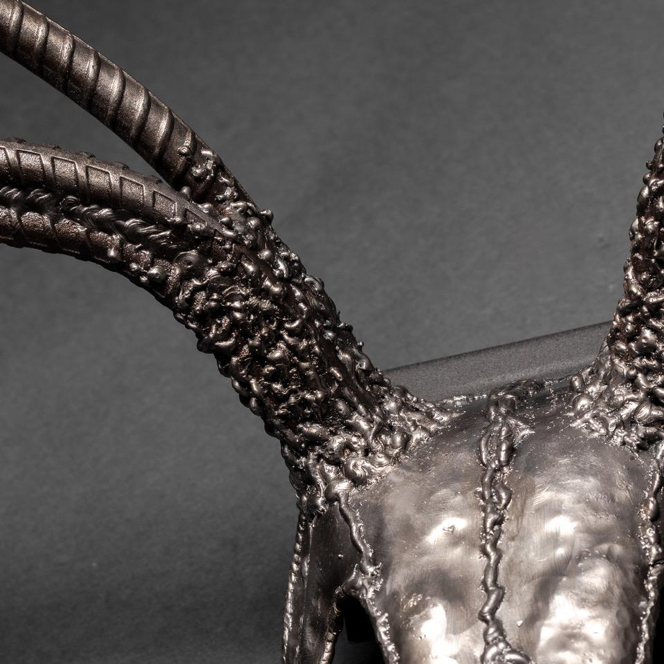 Handcrafted metal sculpture of an eight-point buck skull, showcasing intricate details and a rustic finish.