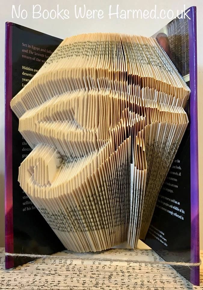 Handcrafted Eye of Horus art made from folded pages of vintage books, showcasing intricate designs and unique colors.