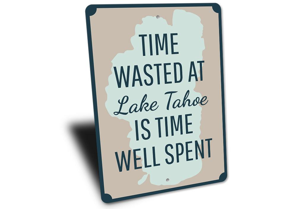 A decorative aluminum sign reading 'Time Wasted at Lake Tahoe', showcasing a beautiful lake scene, perfect for lakehouse decor.