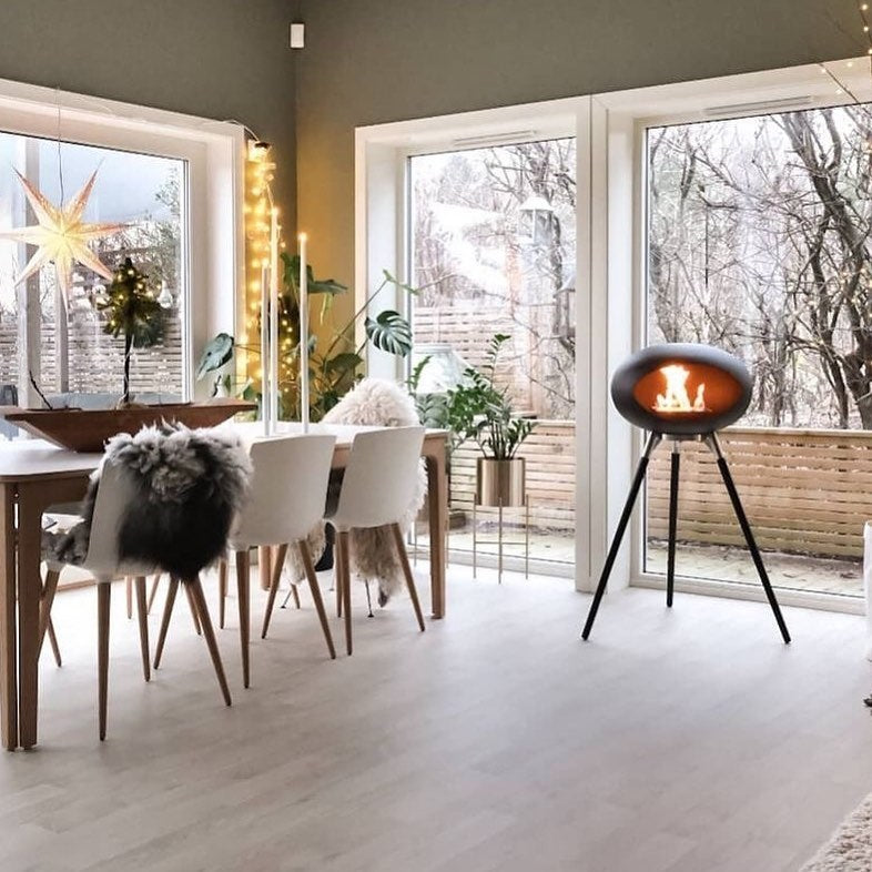 Tripod Indoor + Outdoor Ethanol Fireplace featuring wooden legs and a metal dome, providing a cozy ambiance.