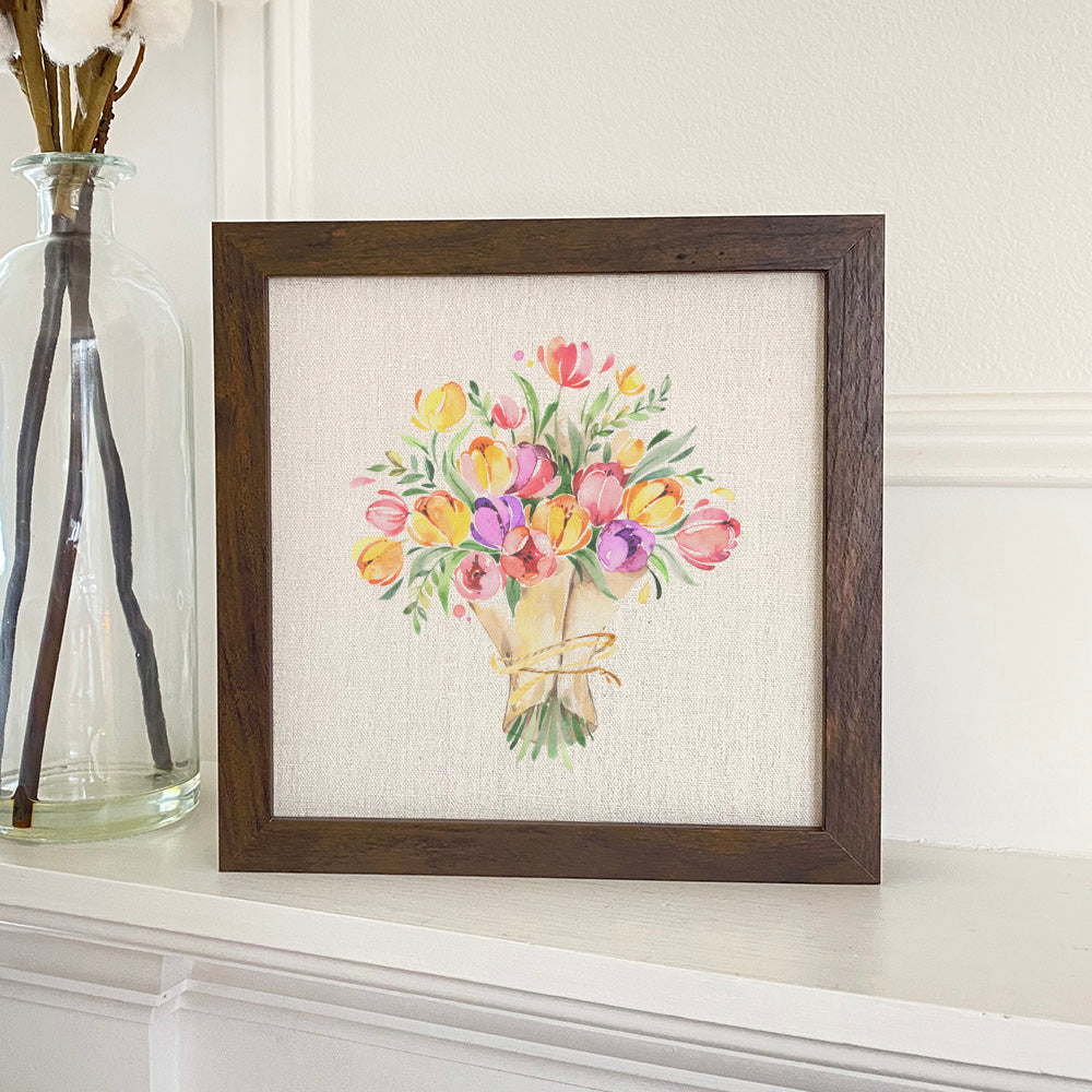 A beautifully framed sign featuring a tulip bouquet design, set against a neutral linen-look background, perfect for home decor.