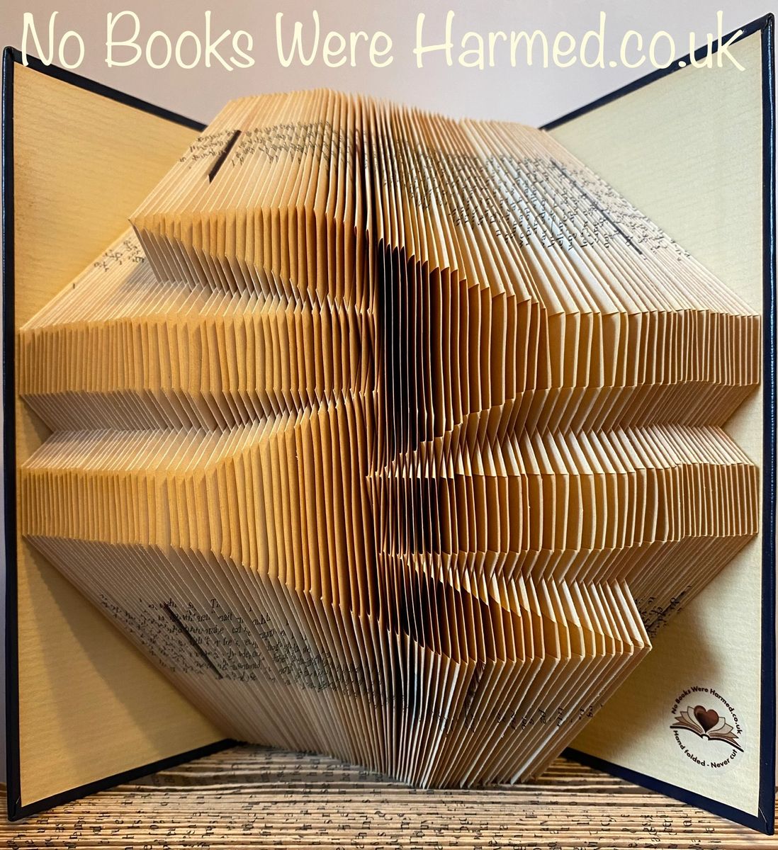 Handcrafted UK Railway symbol art made from vintage book pages, showcasing intricate folds and unique colors.