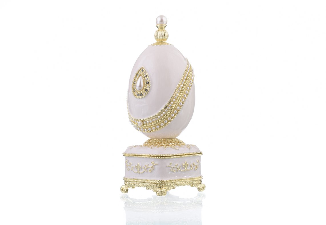 A beautifully crafted White Faberge Egg trinket box adorned with Austrian crystals and a pearl, showcasing intricate enamel painting and luxurious gold or silver plating.