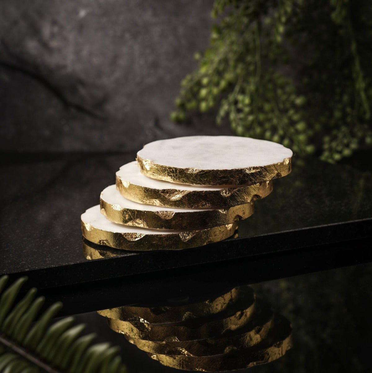 Set of 4 white marble drink coasters with gold, rose gold, and silver edges, elegantly displayed on a wooden table.