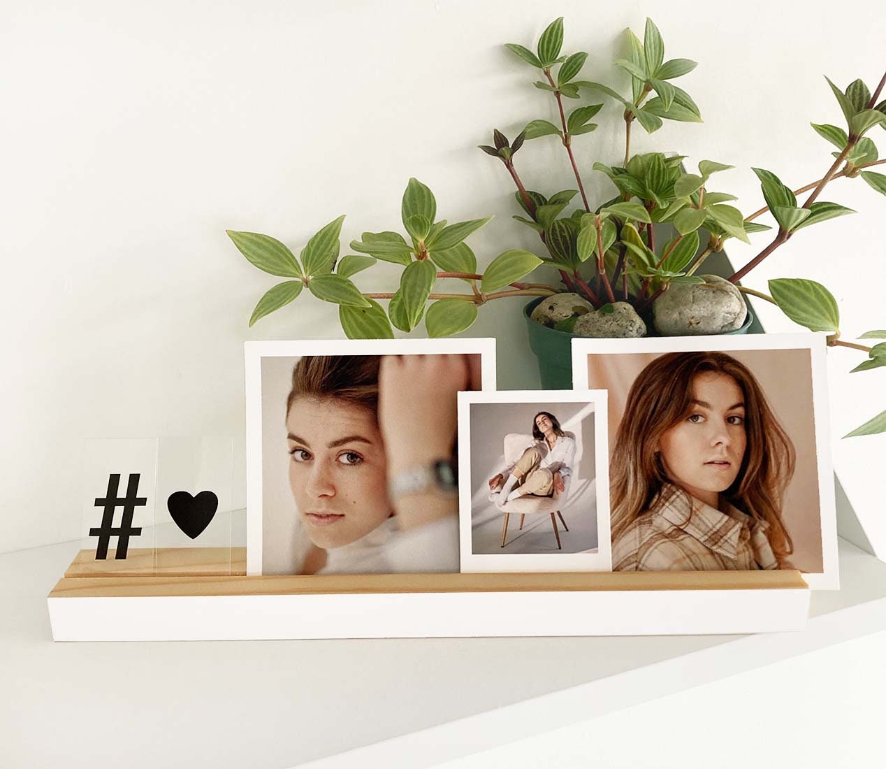 A stylish white wood photo ledge displaying various photos and art prints, showcasing its versatility and elegant design.