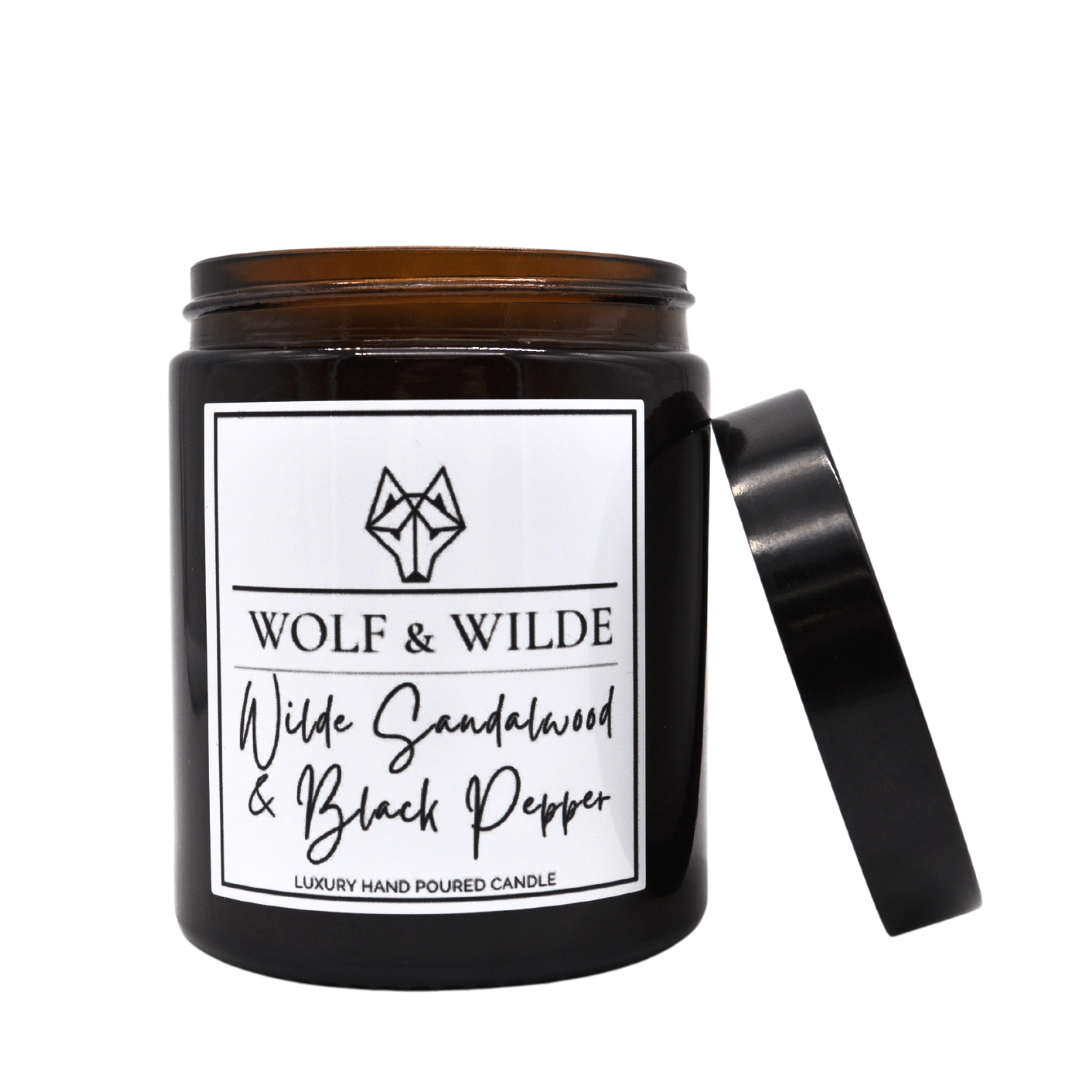 Wilde Sandalwood & Black Pepper Luxury Aromatherapy Scented Candle in an elegant glass jar with a flickering flame.