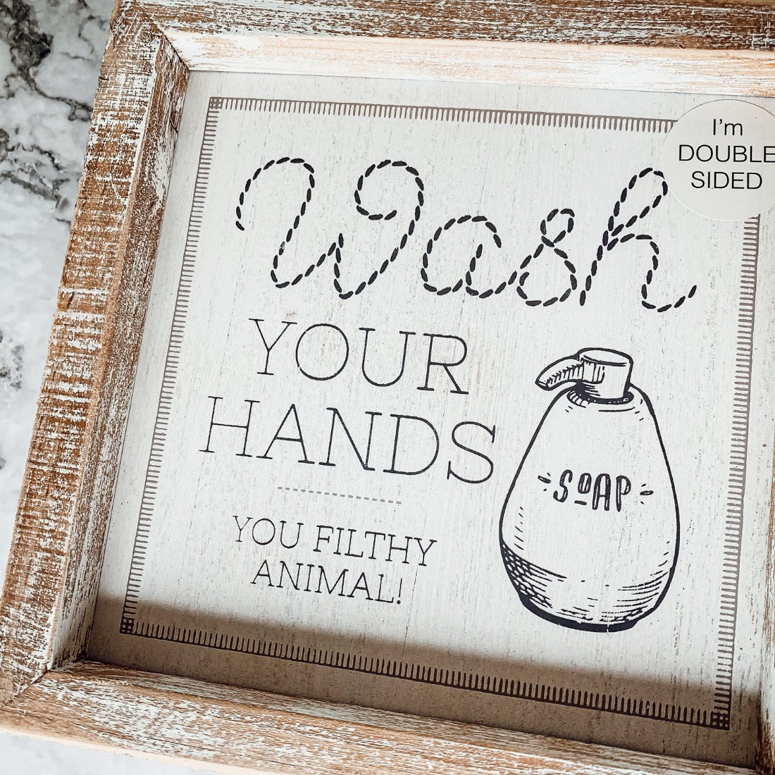Wipe It Real Good Double-Sided sign with humorous bathroom messages in a wooden frame, displayed freestanding.