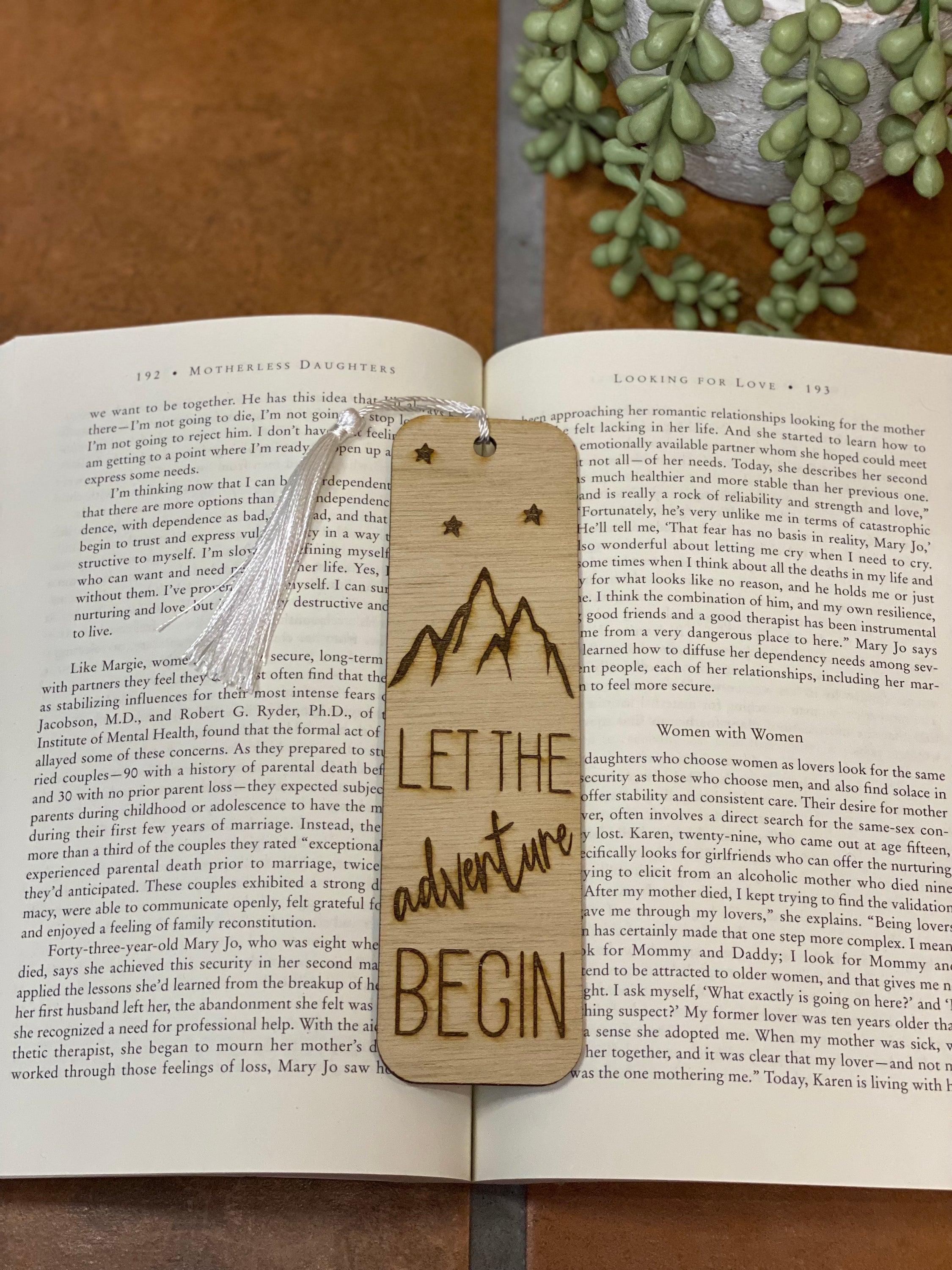 A beautifully crafted wooden bookmark with intricate laser engraving and a white tassel, perfect for book lovers.