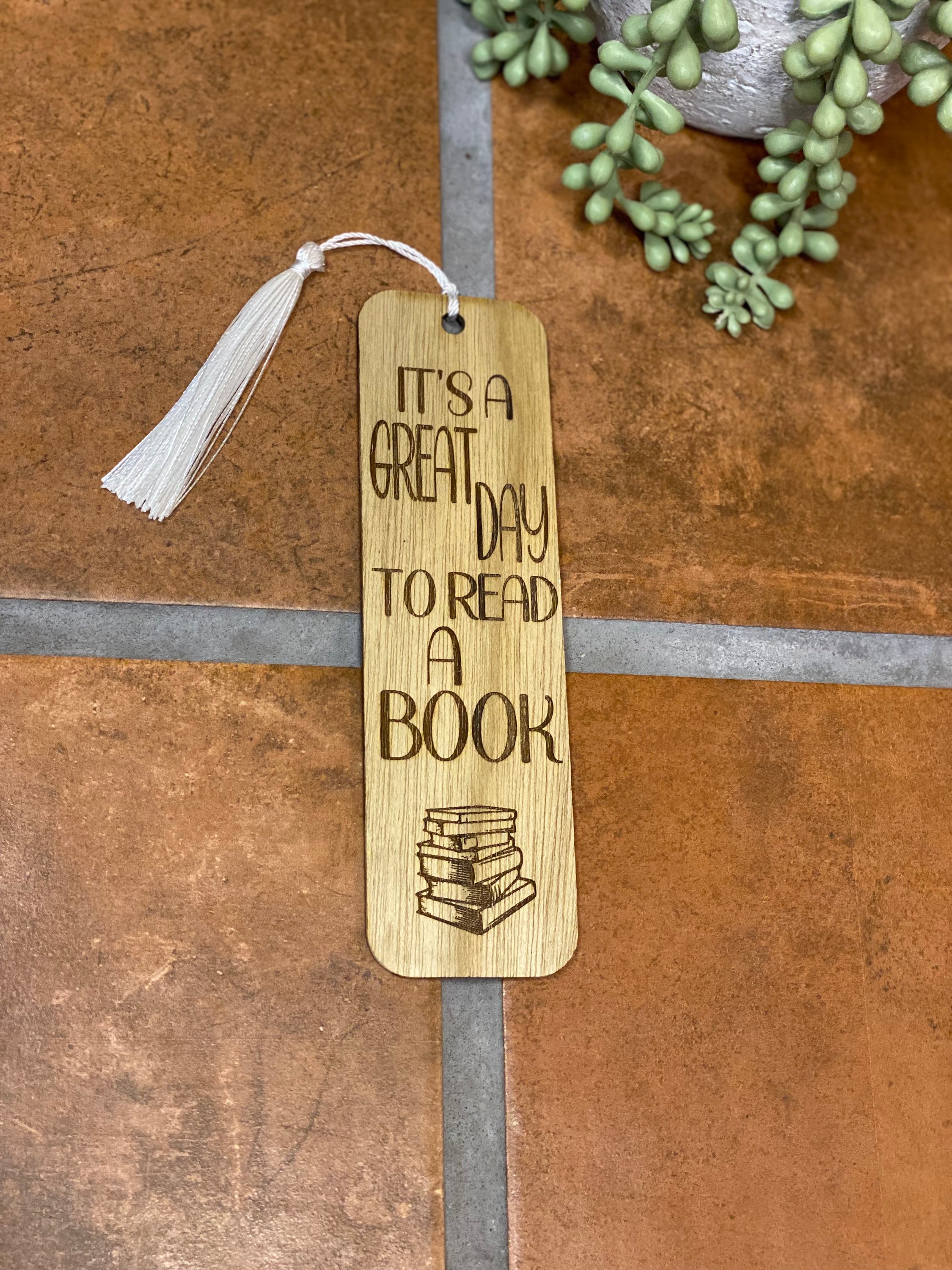 A beautifully crafted wooden bookmark with a white tassel, showcasing unique laser engraved designs.