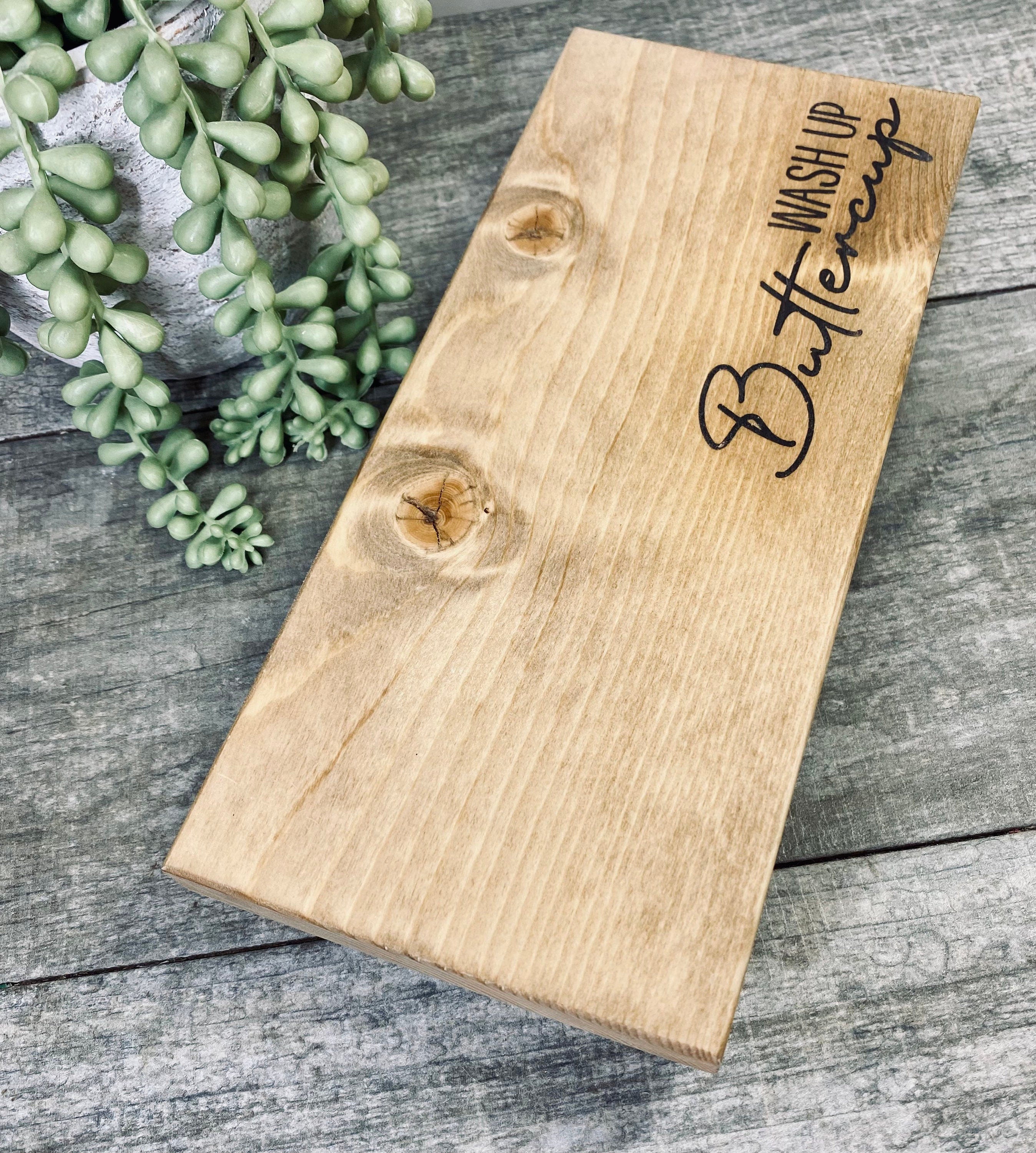Handmade wooden riser with 'wash up buttercup' design, showcasing unique wood grain and oil-based stain, perfect for bathroom or kitchen decor.