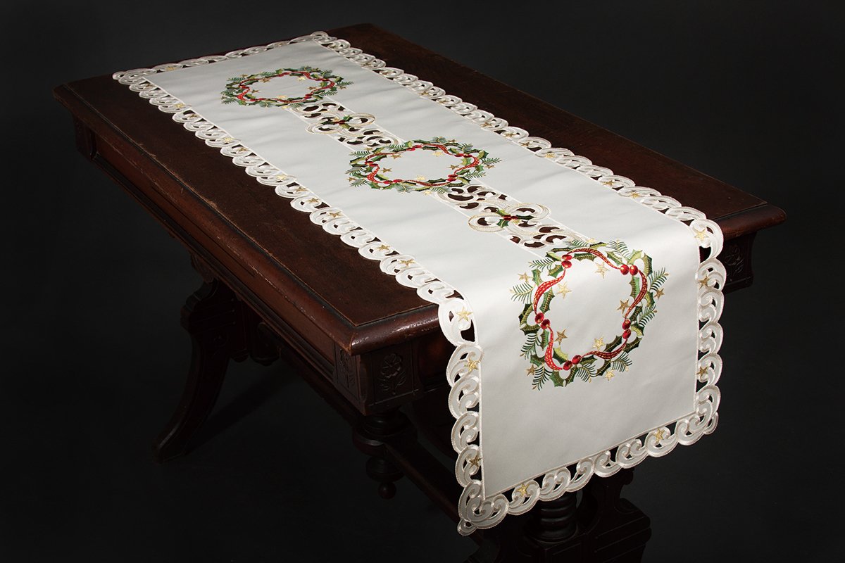 XD17103 Ribbon Wreath Table Runner featuring embroidered Christmas holly wreaths and berries on ivory cutwork.
