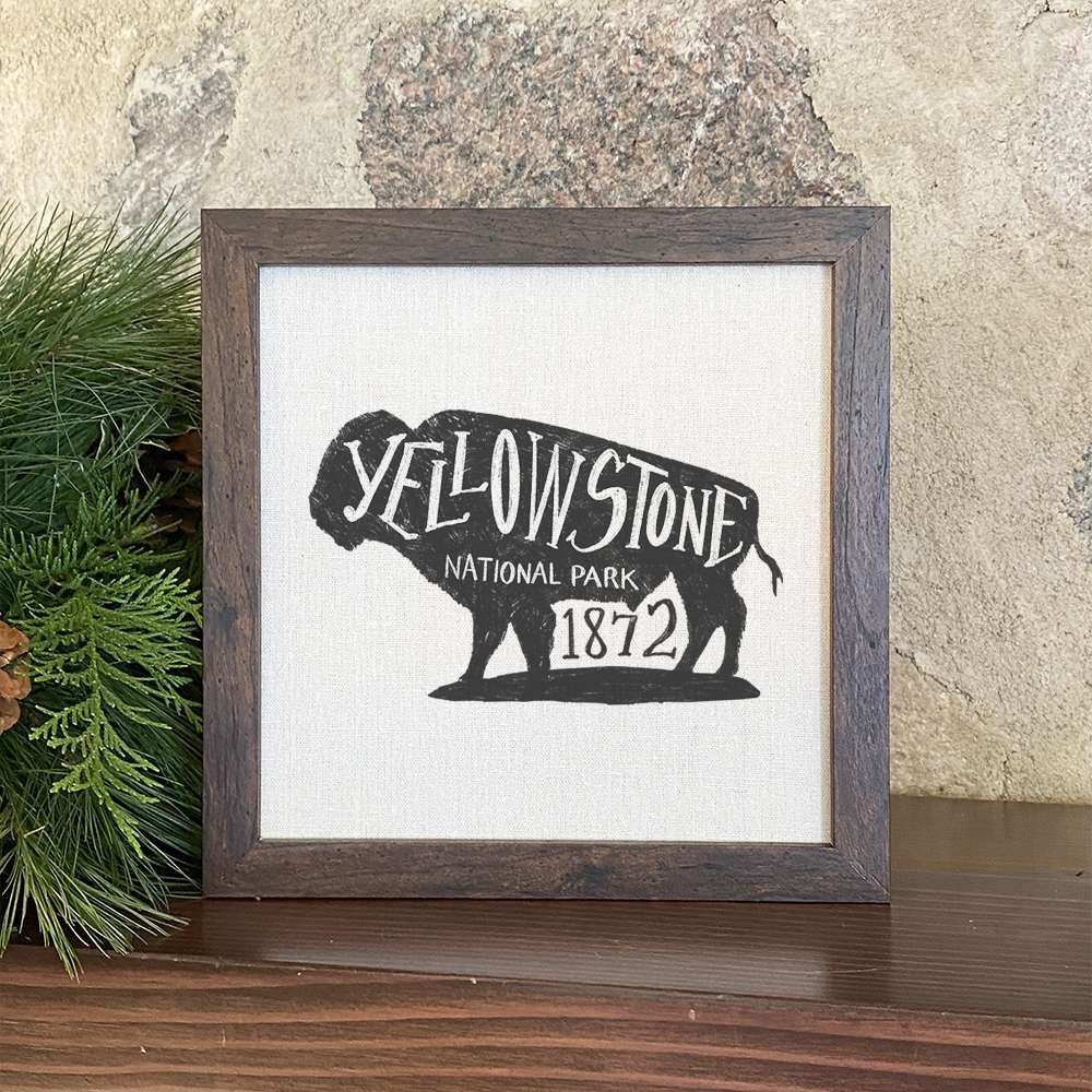 Framed sign featuring a buffalo design, set in a stylish wood frame with a linen-look background, perfect for home decor.