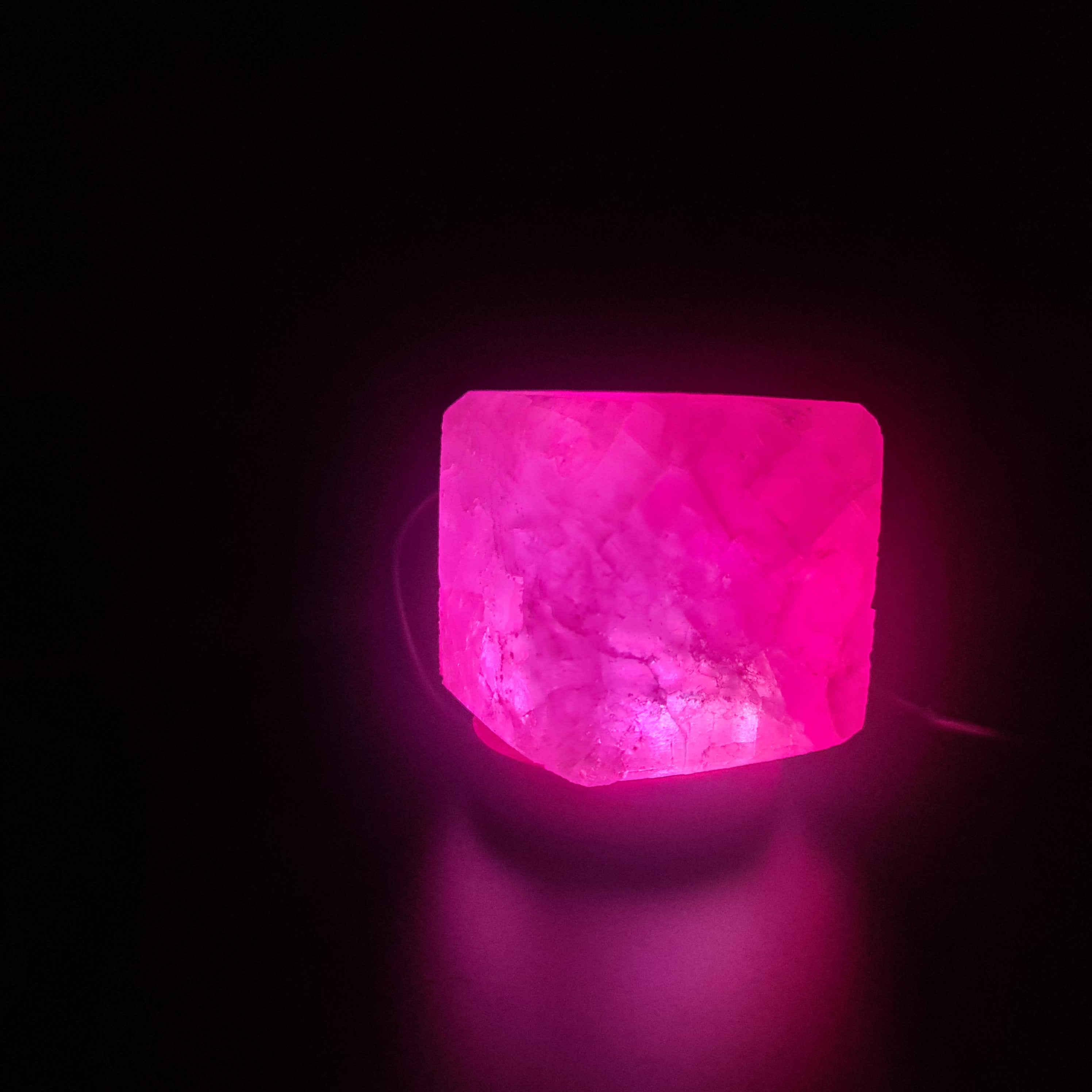 Himalaya USB Farbwechsellampe aus rosa Himalaya-Salz auf Holzsockel, strahlt warmes, beruhigendes Licht aus.