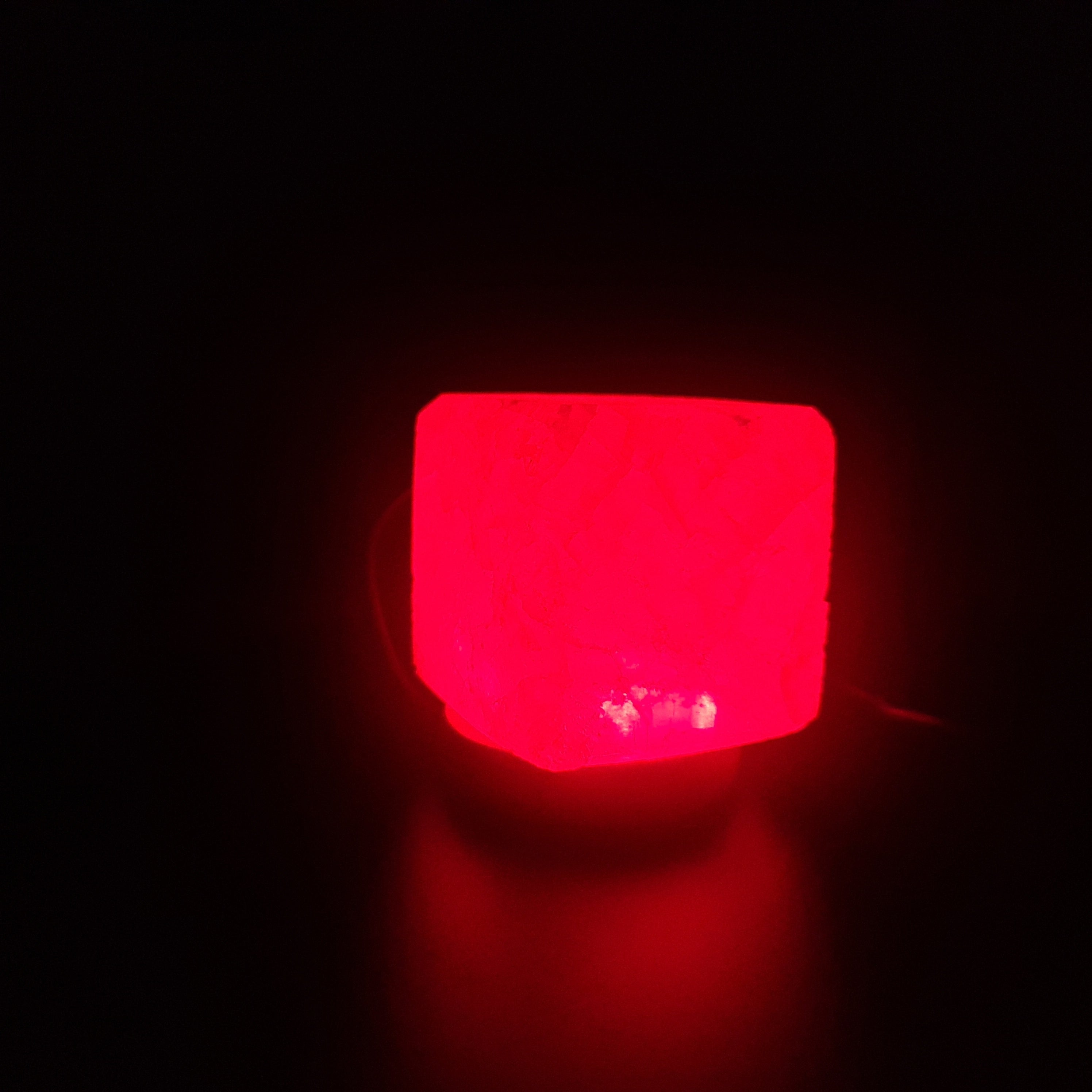 Himalaya USB Farbwechsellampe aus rosa Himalaya-Salz auf Holzsockel, strahlt warmes, beruhigendes Licht aus.